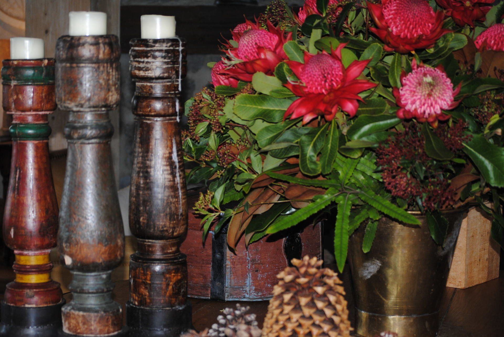 A bunch of candles are sitting on a table next to a vase of flowers.