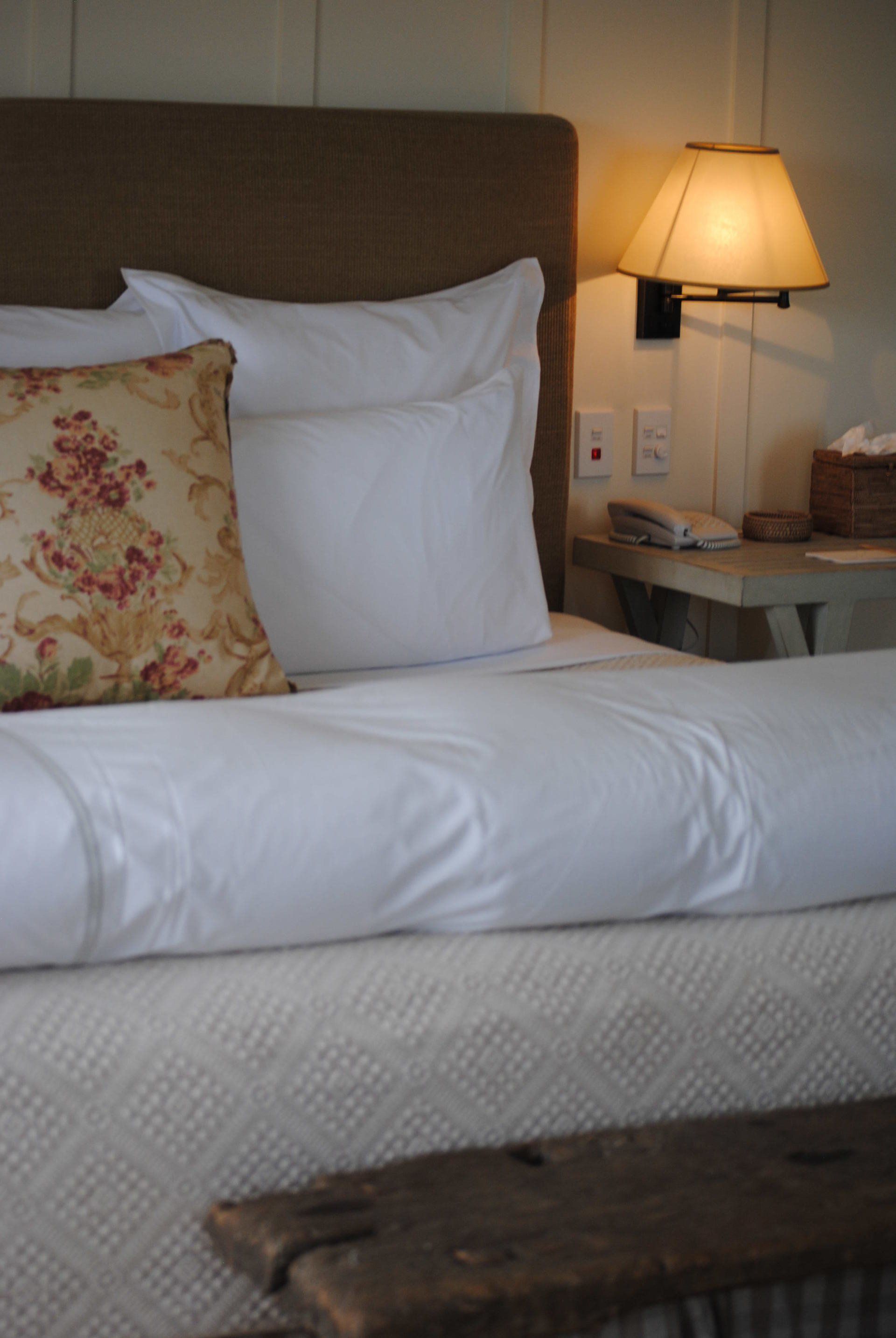 A bed with white sheets and a floral pillow on it