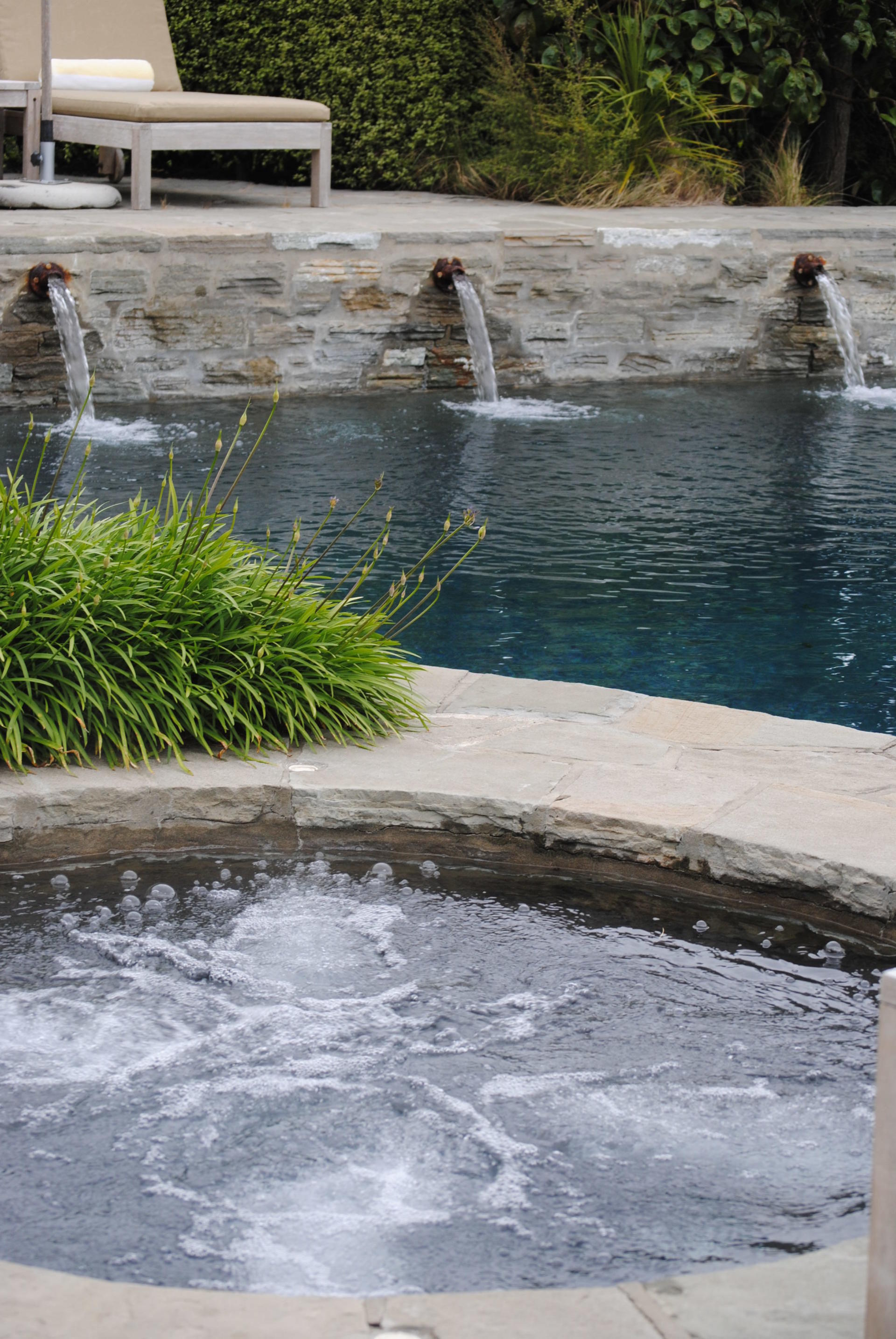 A swimming pool with a fountain in the middle of it