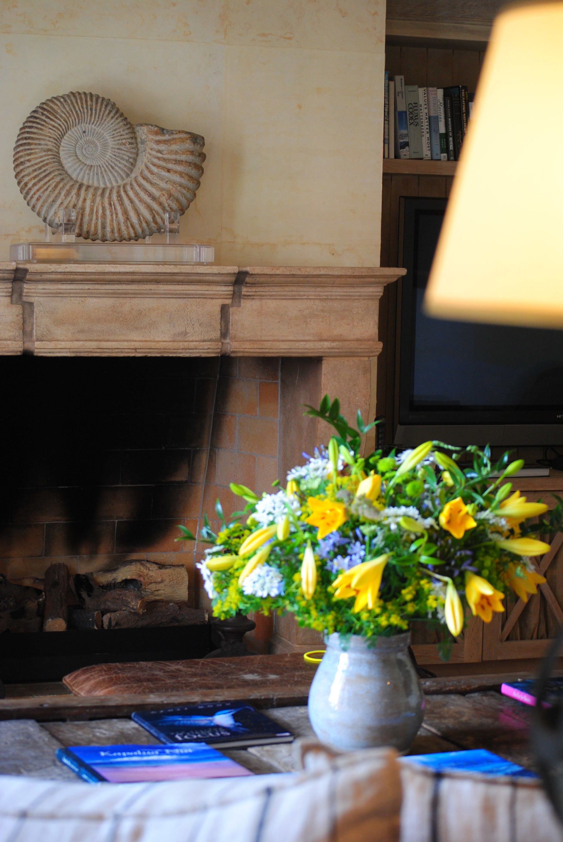 A vase of flowers is sitting on a table in front of a fireplace.