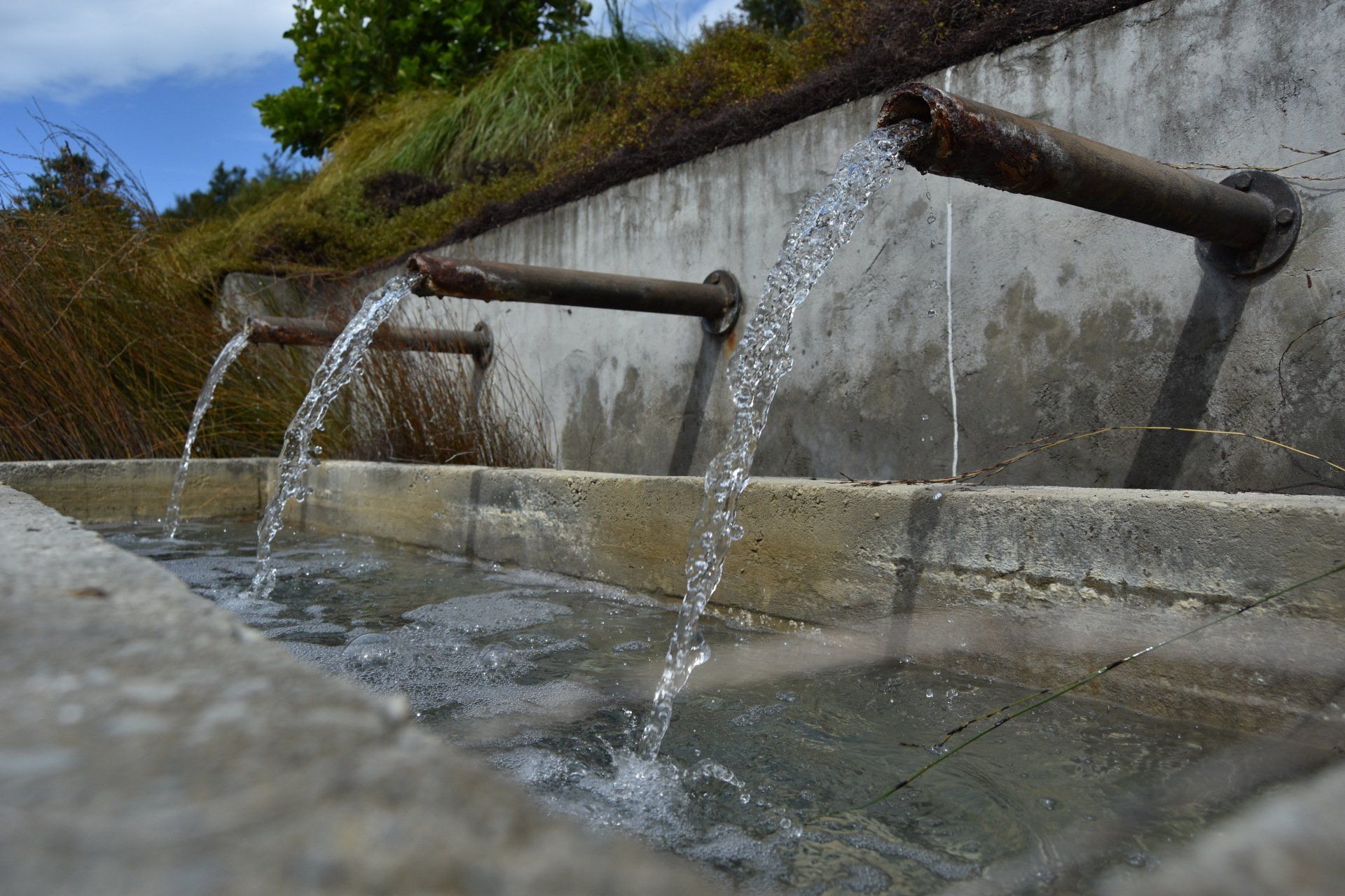 A fountain with water coming out of three pipes.
