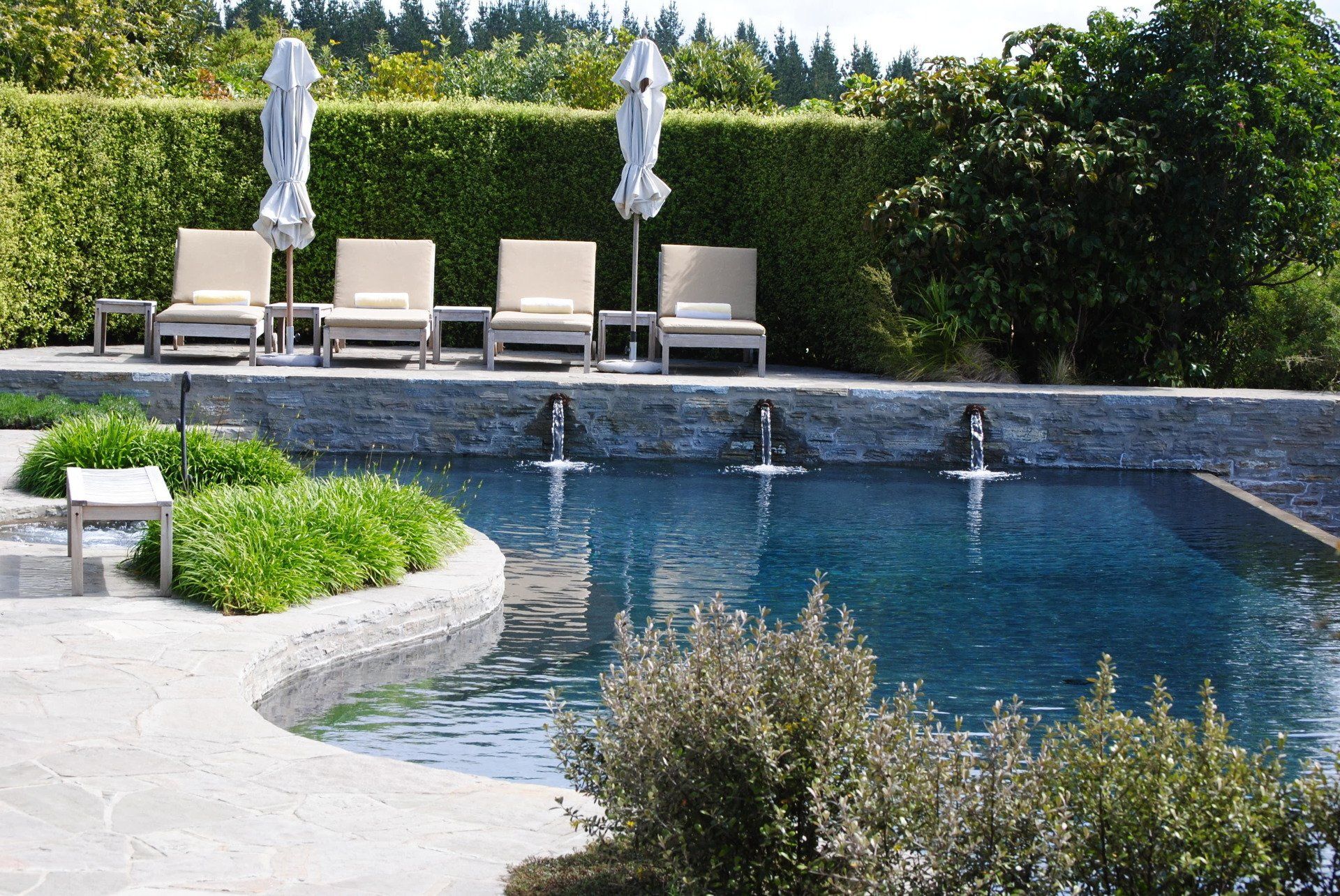 A large swimming pool surrounded by chairs and umbrellas