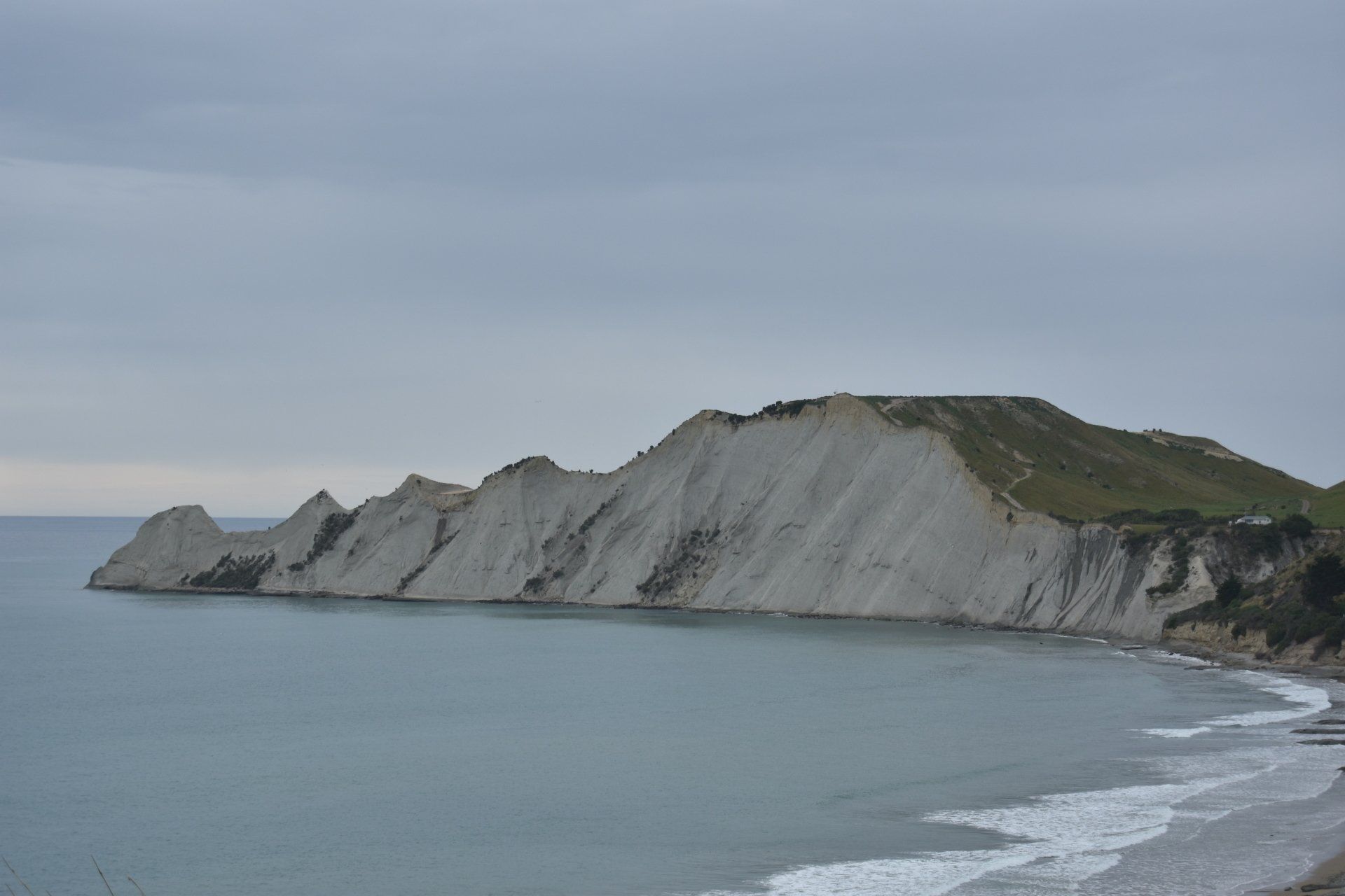 A beach with a mountain in the background and a large body of water.