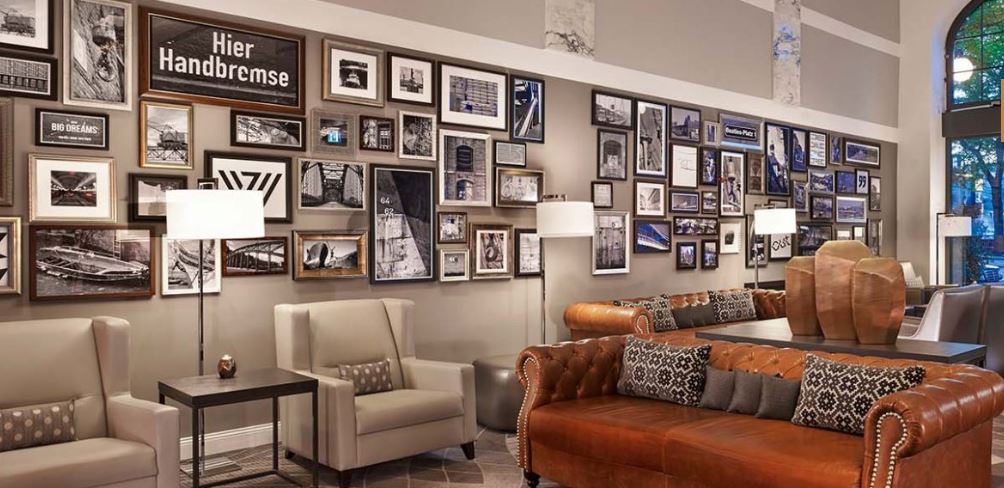 A living room with a couch , chairs , lamps and a wall filled with pictures.