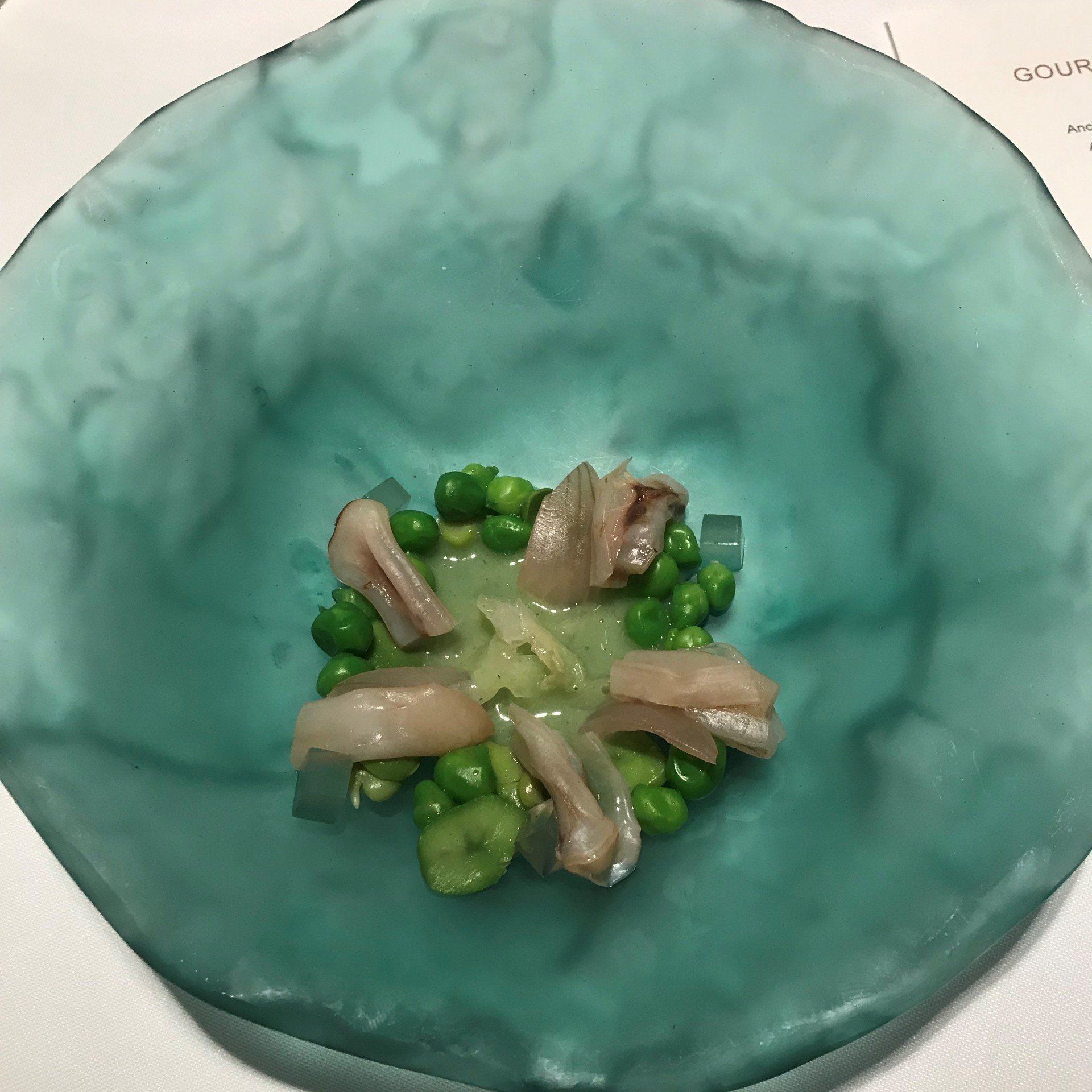 A blue bowl filled with green peas and meat
