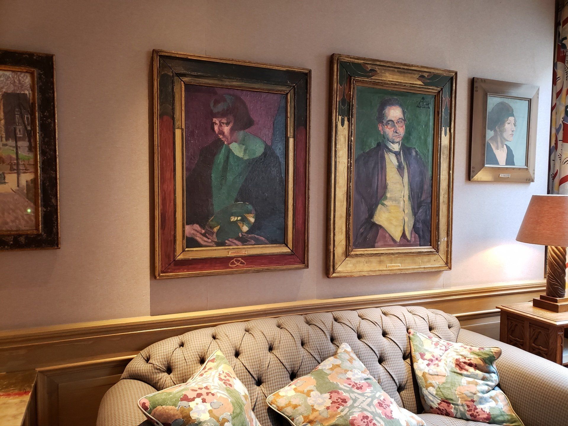 A living room with a couch and two paintings on the wall.