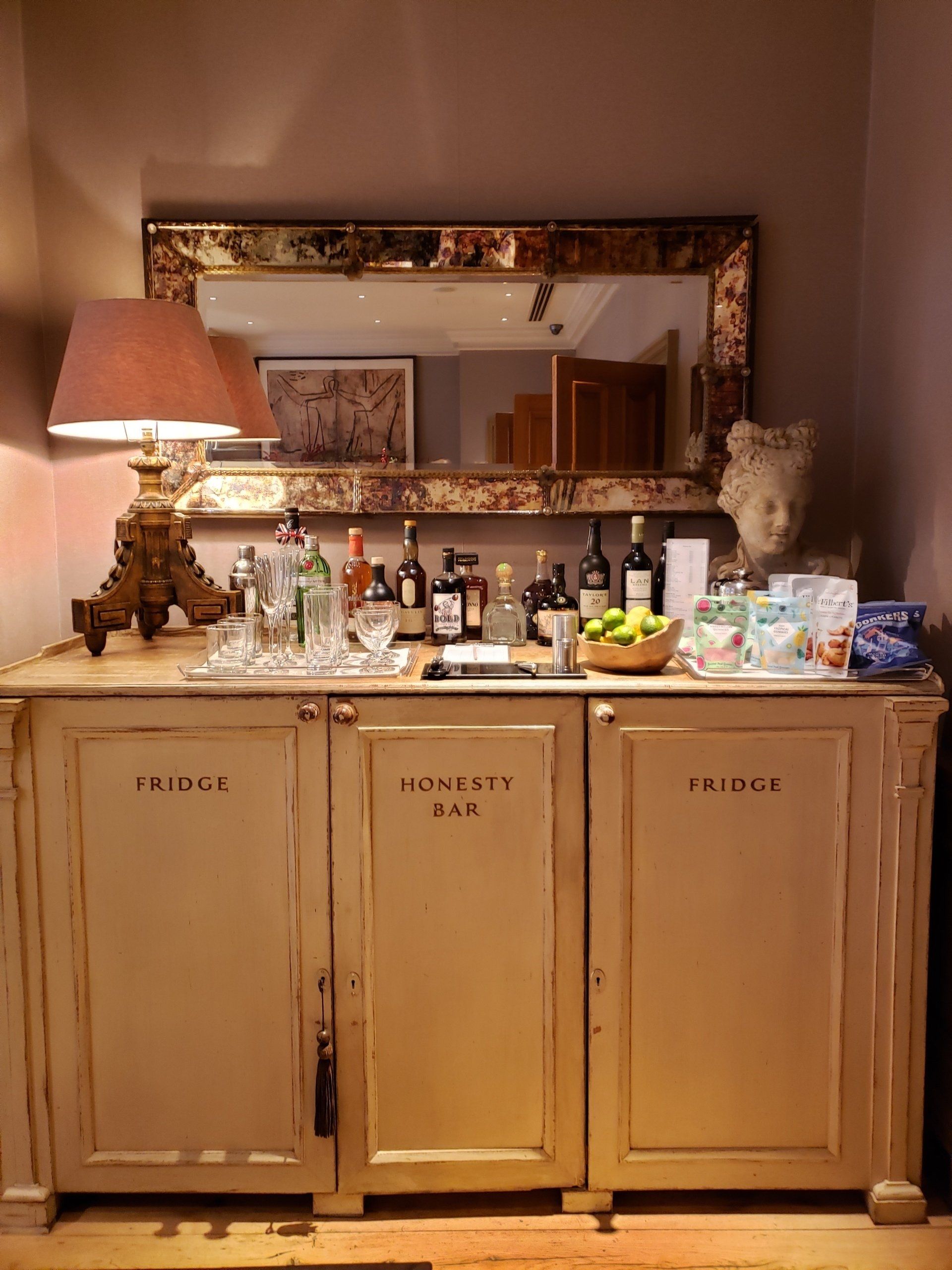 A buffet with bottles of liquor and a lamp on it