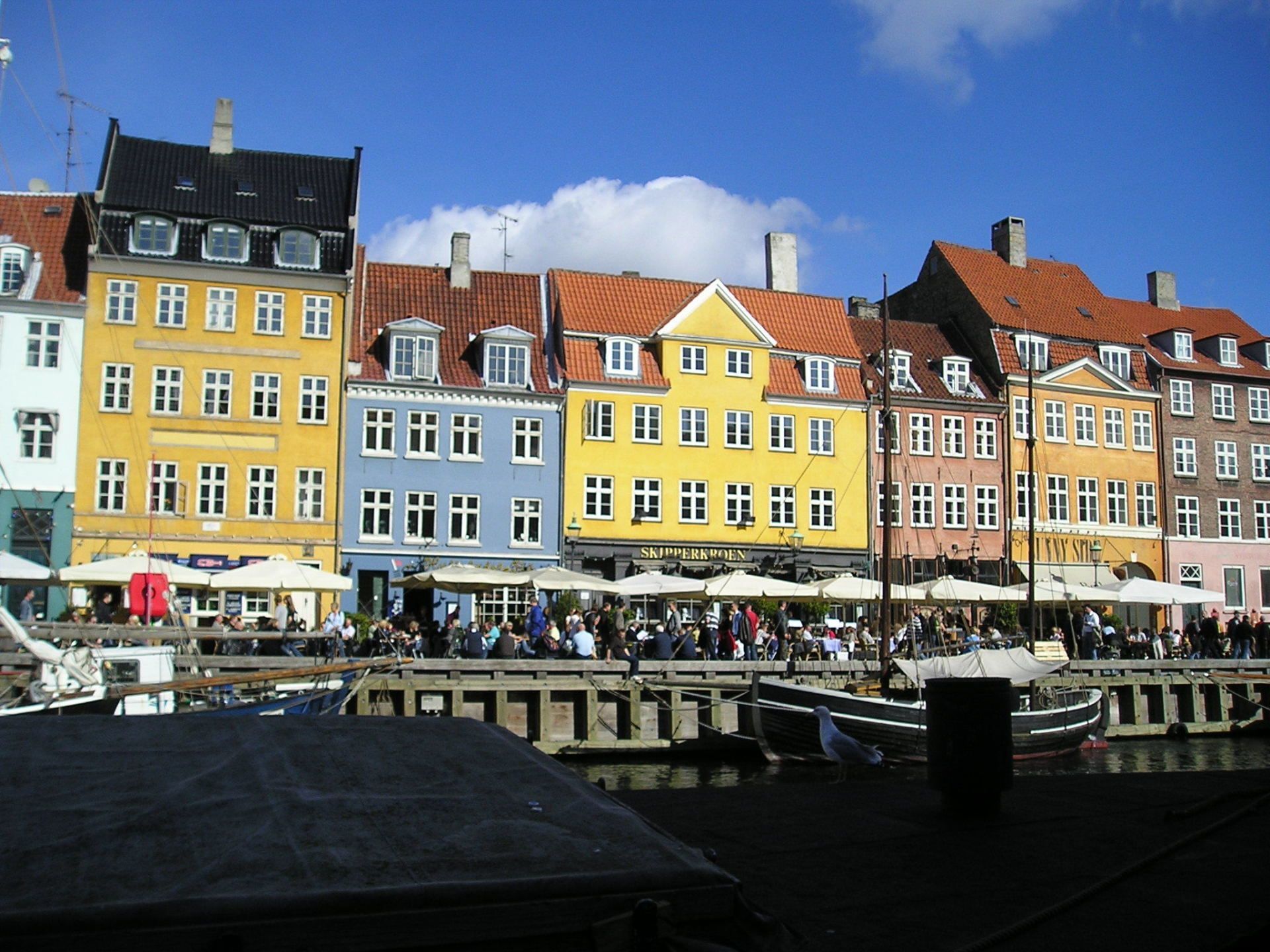 A group of people are gathered in front of a row of buildings