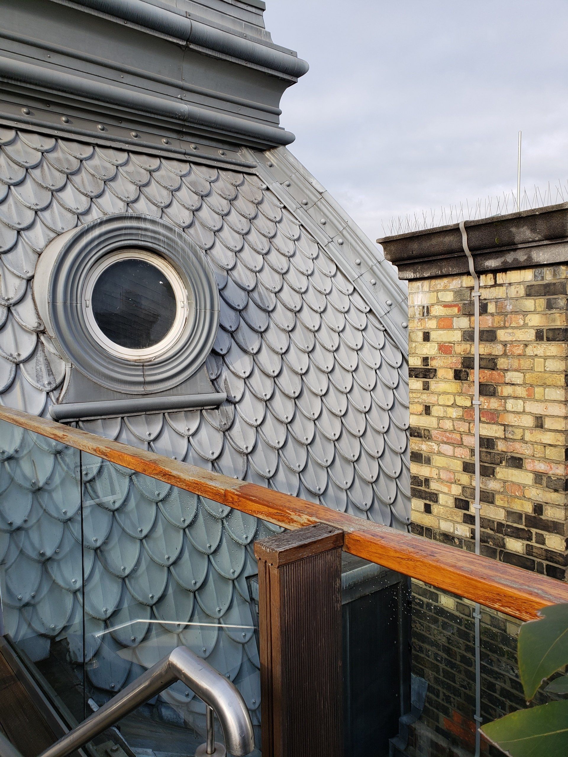 A roof with a round window on it and a wooden railing.