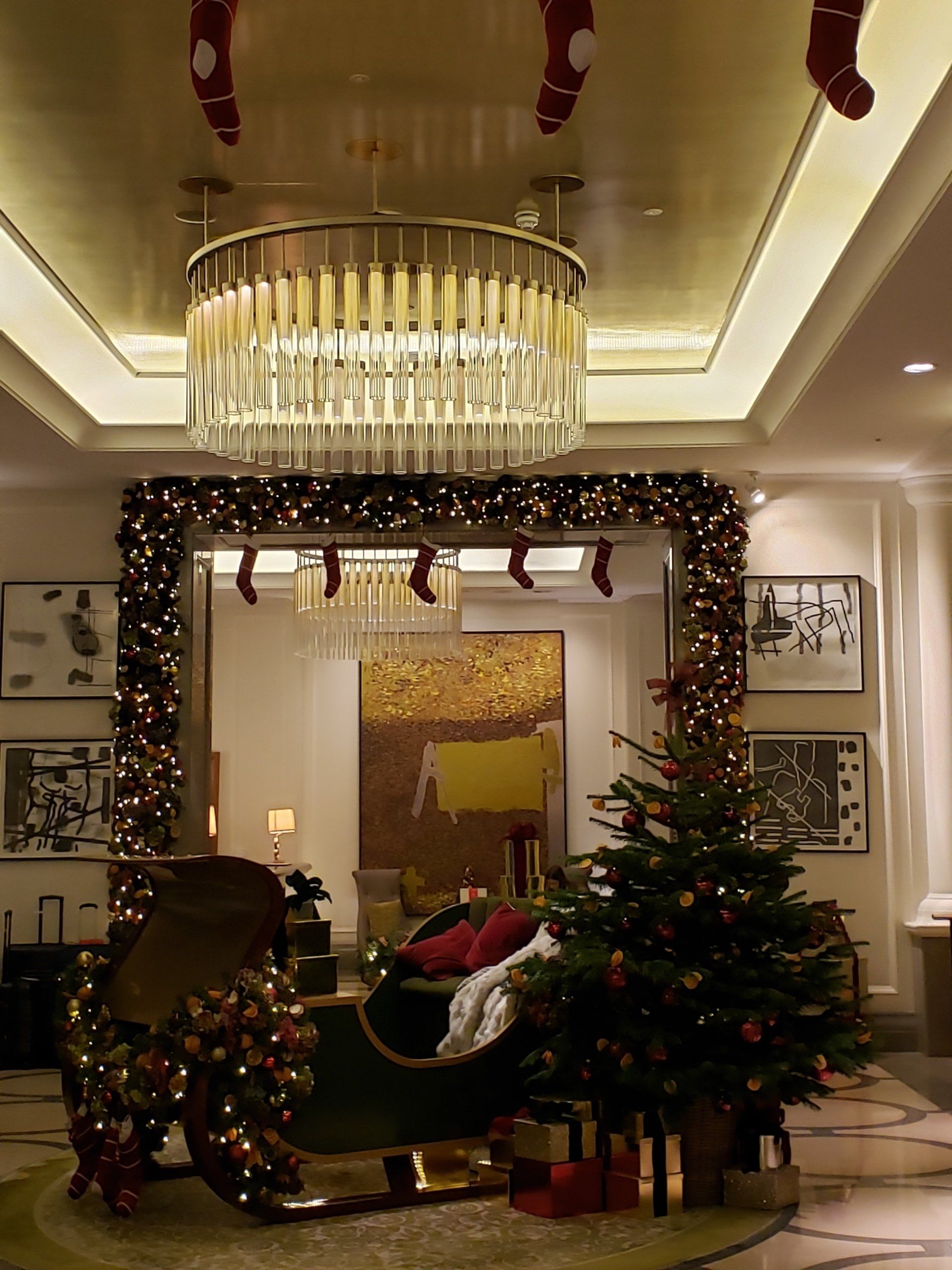 A room decorated for christmas with a sleigh and a christmas tree
