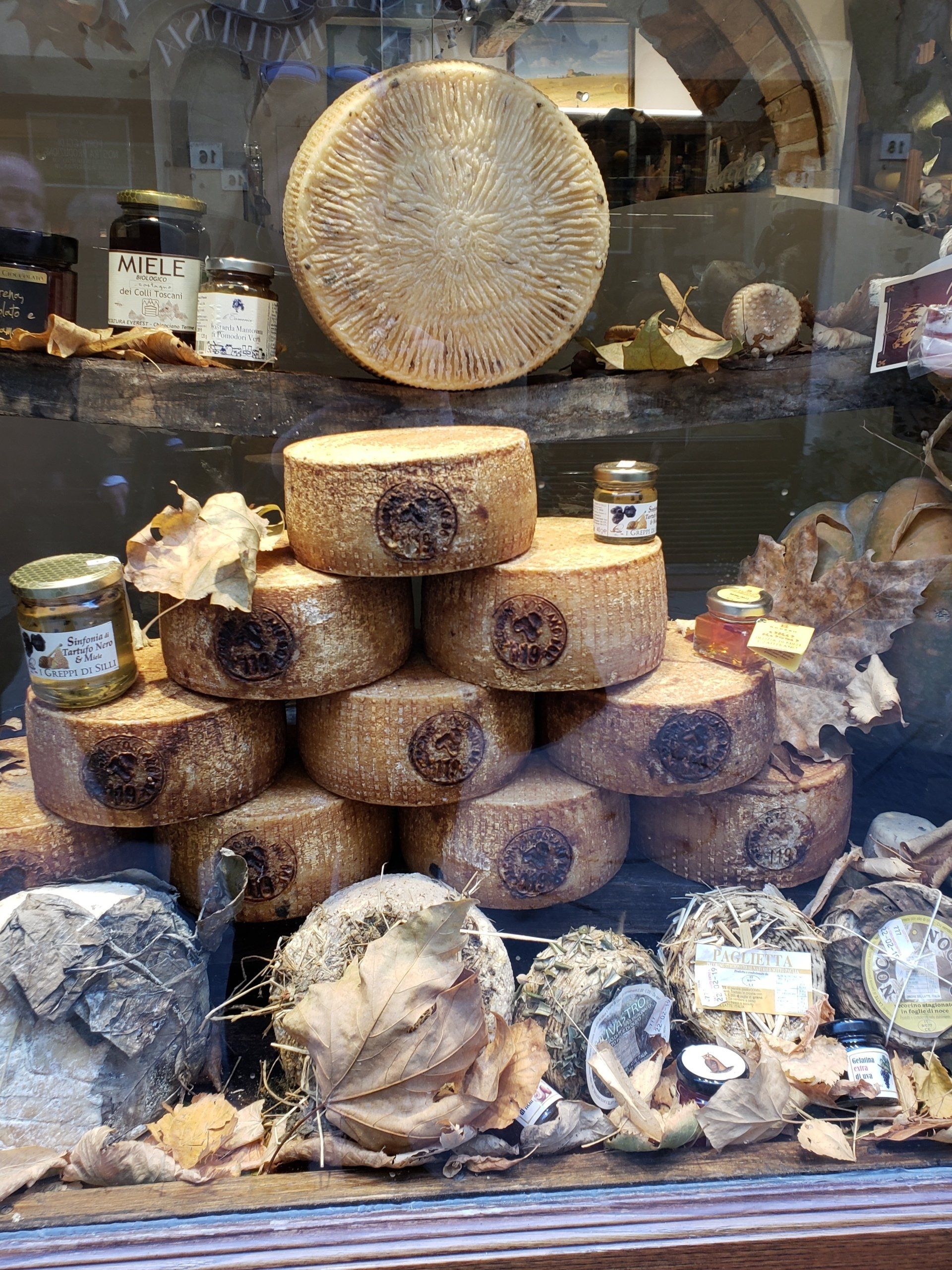 A variety of cheeses are stacked on top of each other in a store window.