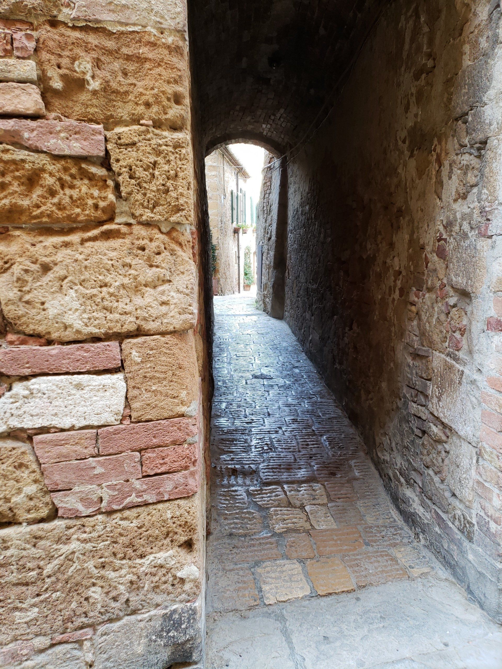 A narrow stone tunnel between two brick walls.