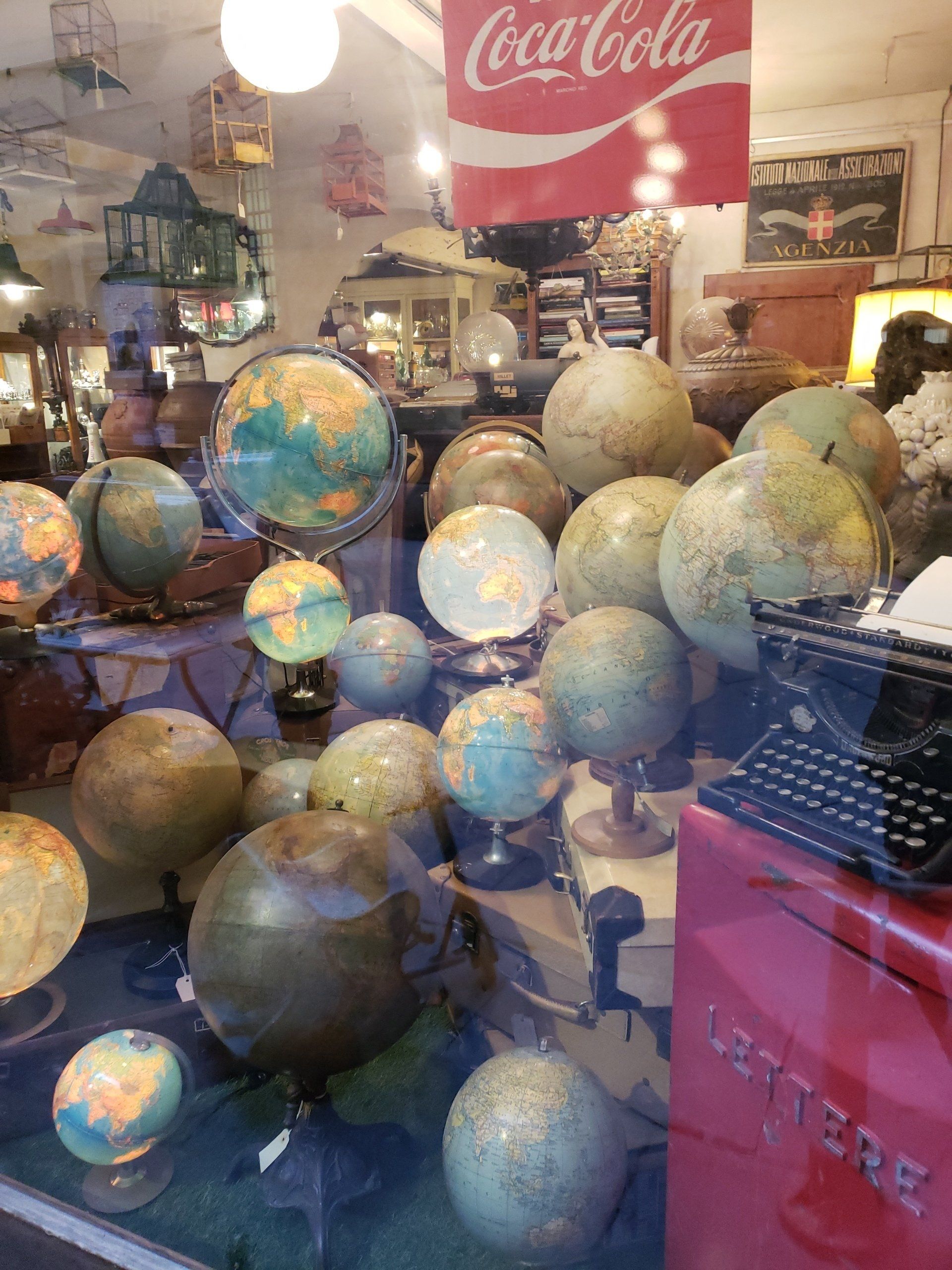 A coca cola sign hangs above a display of globes