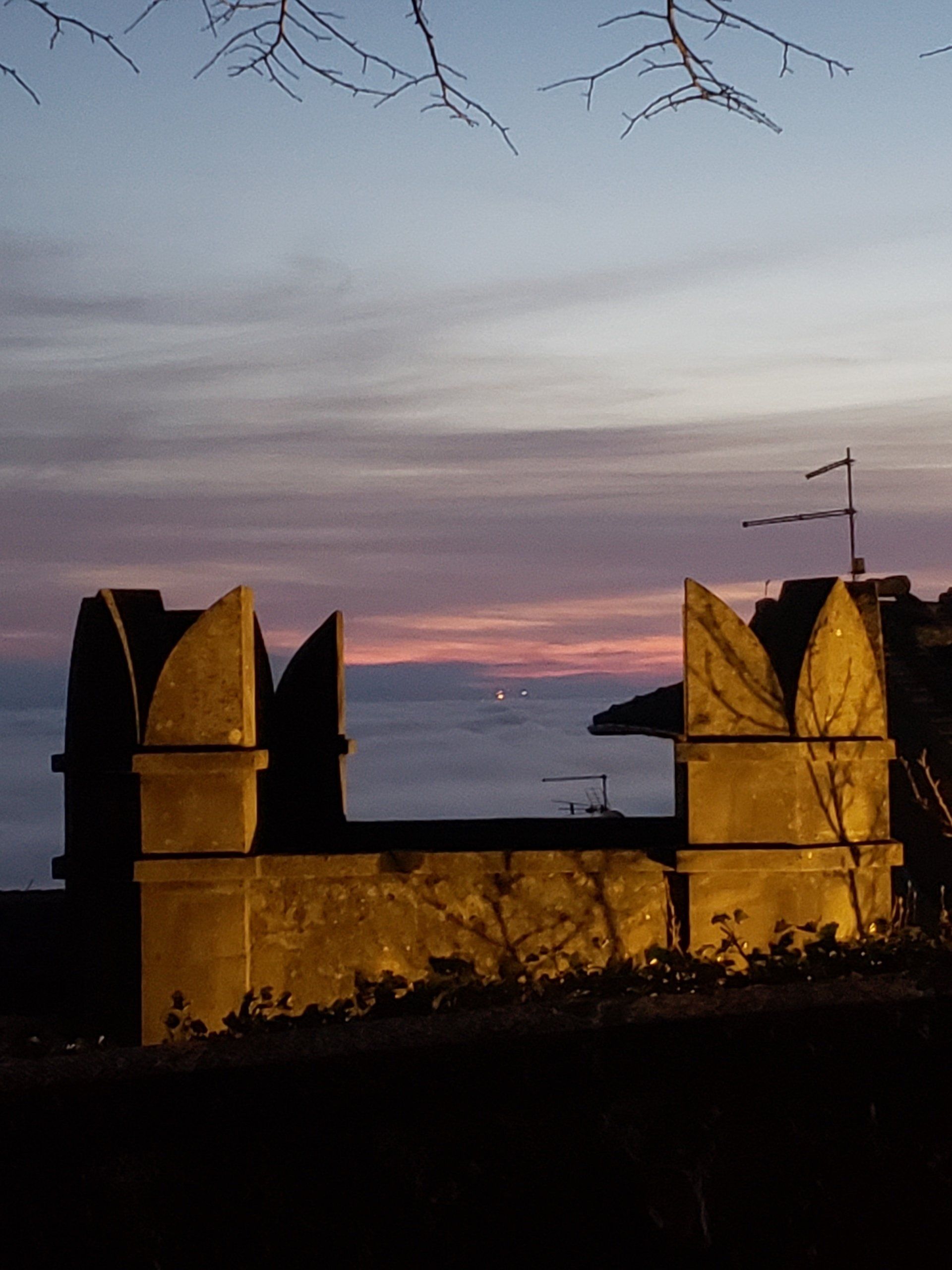 A sunset over a body of water with a building in the foreground