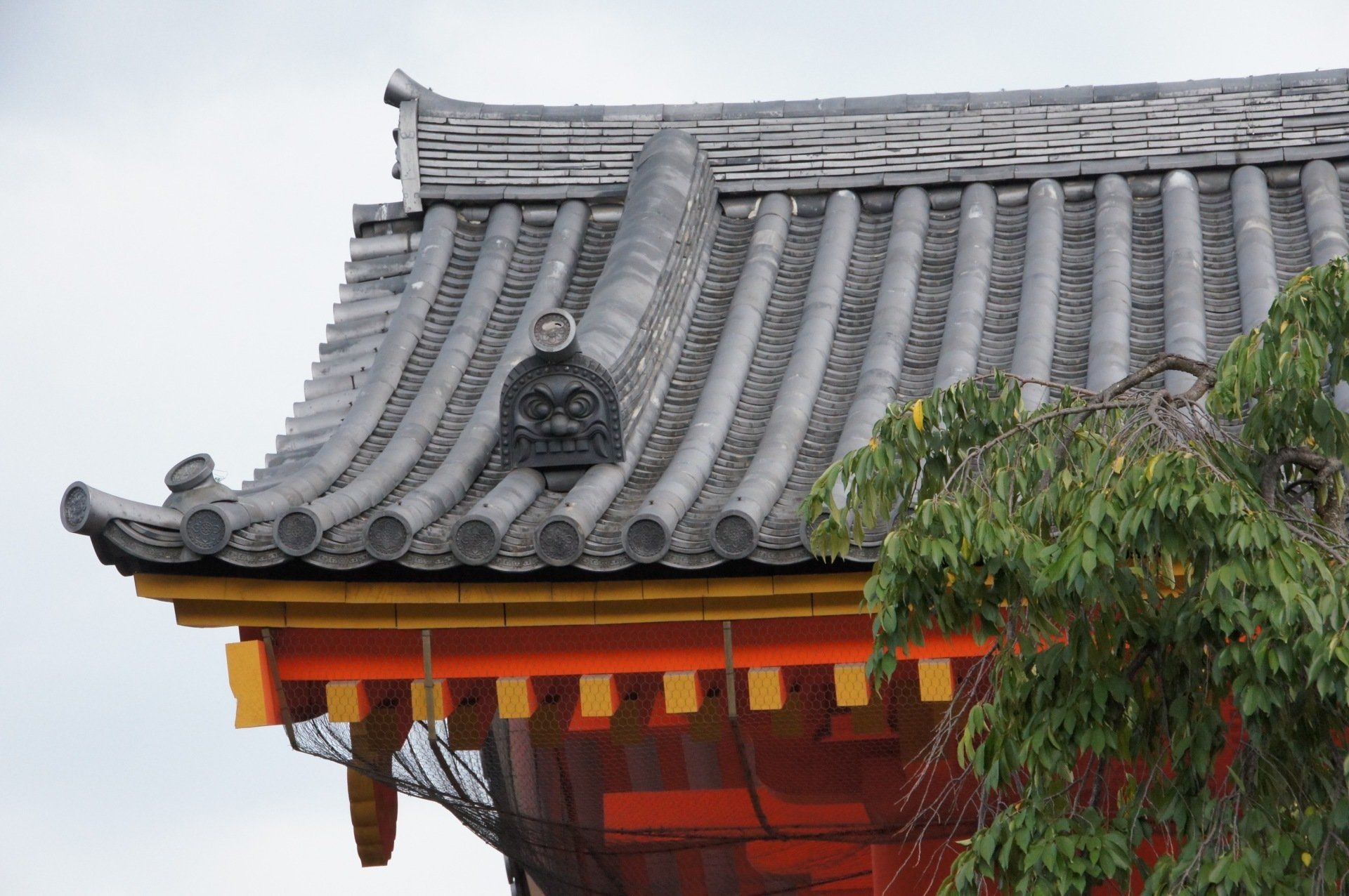A close up of a roof of a building with a tree in the foreground.
