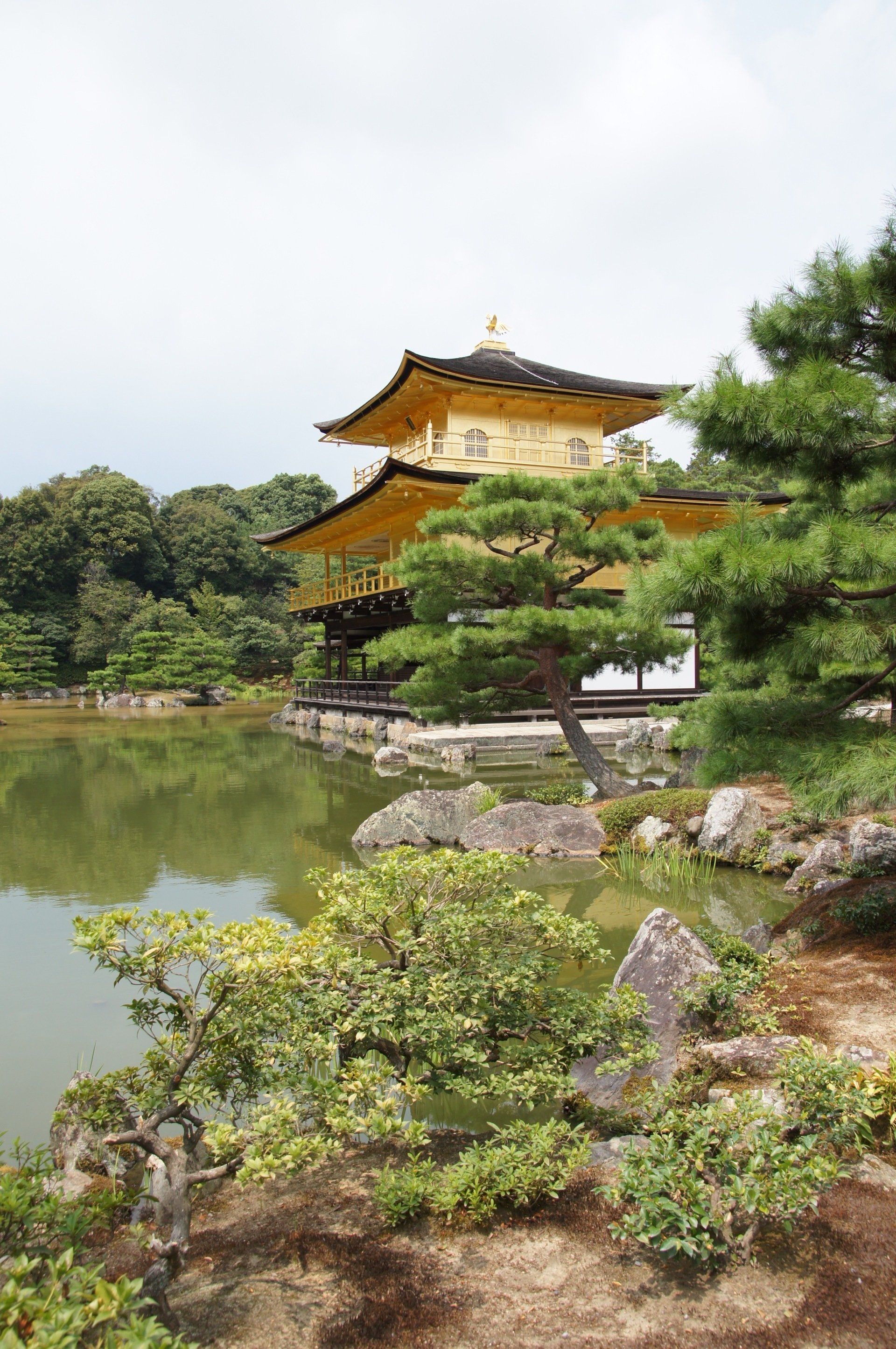 There is a temple in the middle of a park next to a lake.