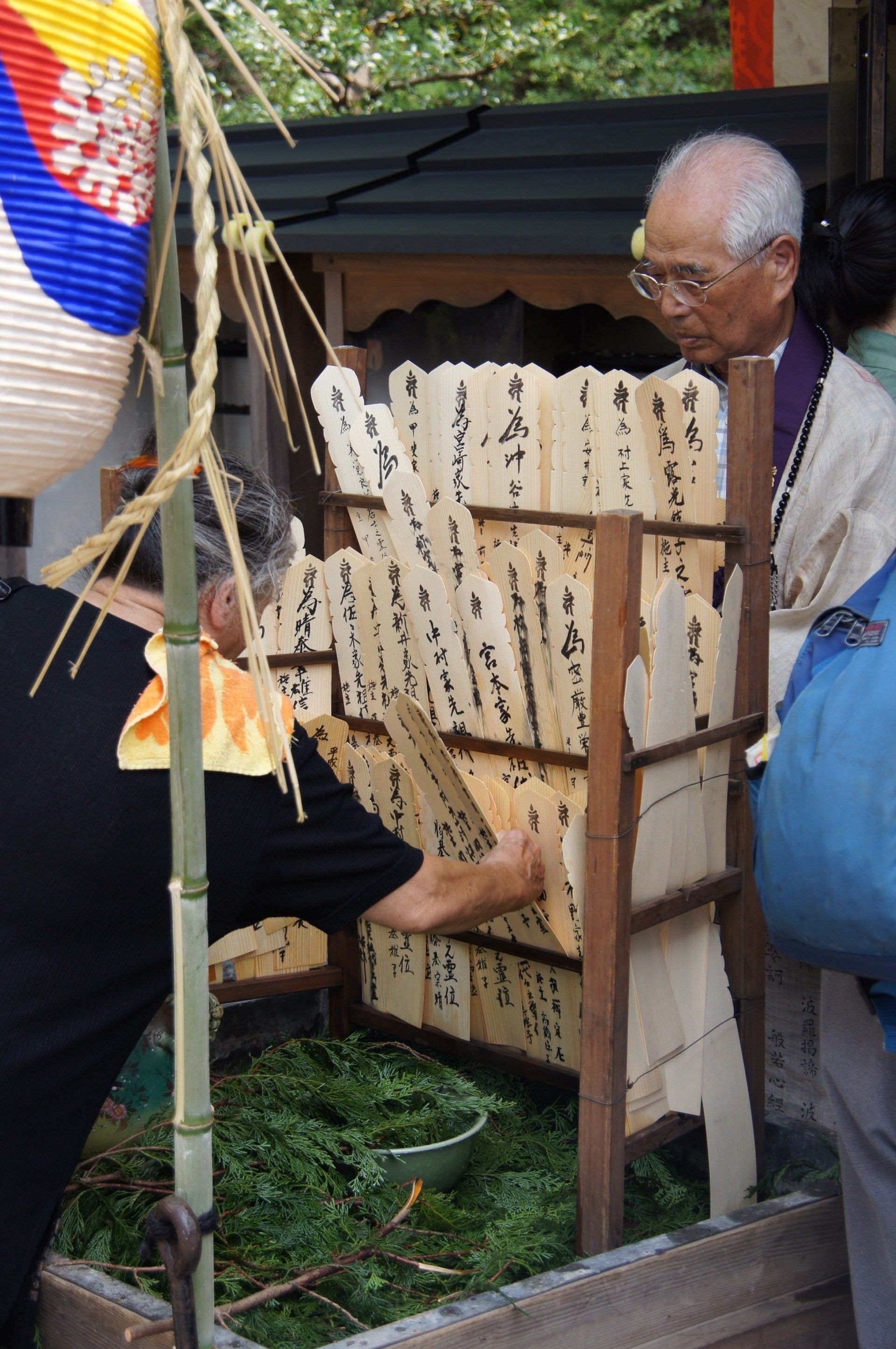 A man is standing in front of a wooden fence with chinese writing on it