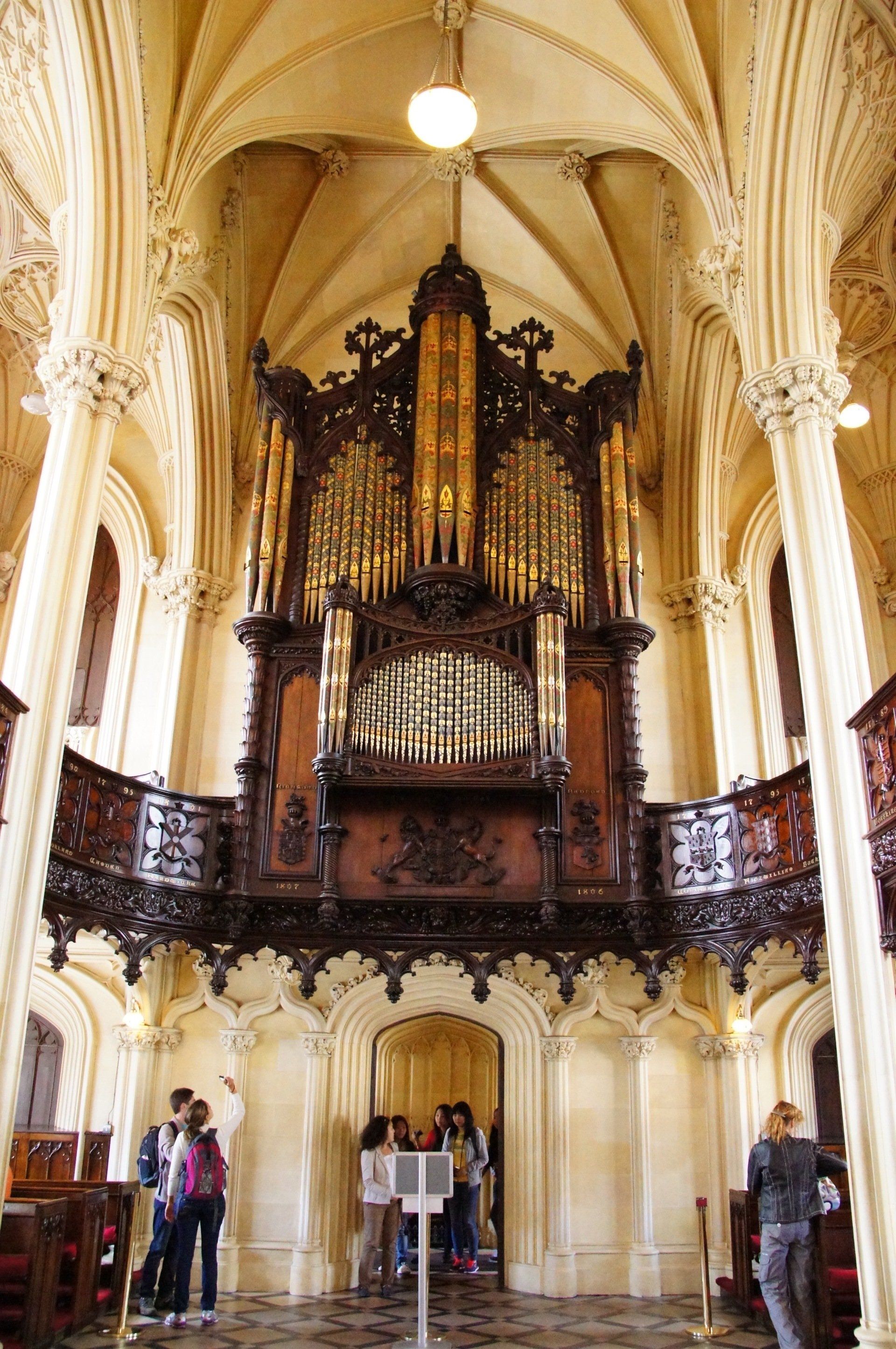 A group of people are standing in front of a large organ in a church.