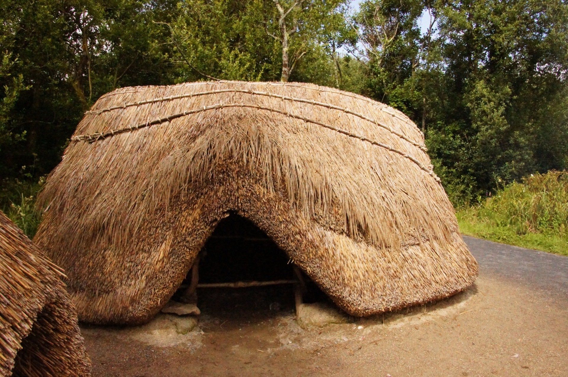 A thatched hut is sitting on the side of a road.