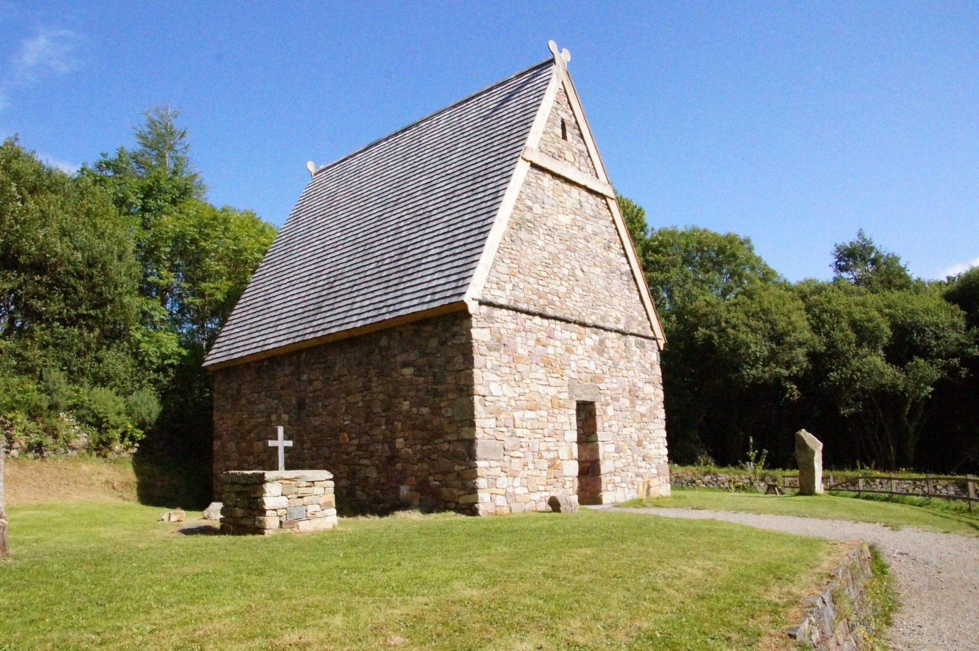A small stone church with a cross in front of it