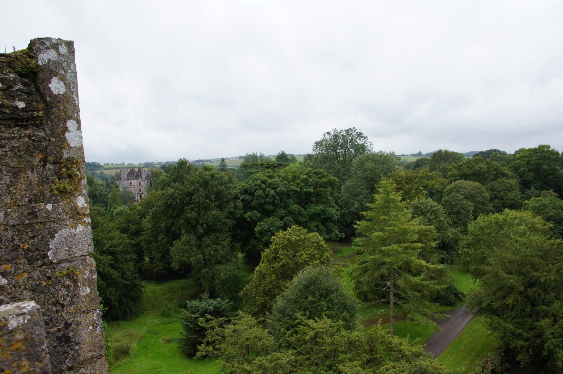 An aerial view of a castle surrounded by trees on a cloudy day.
