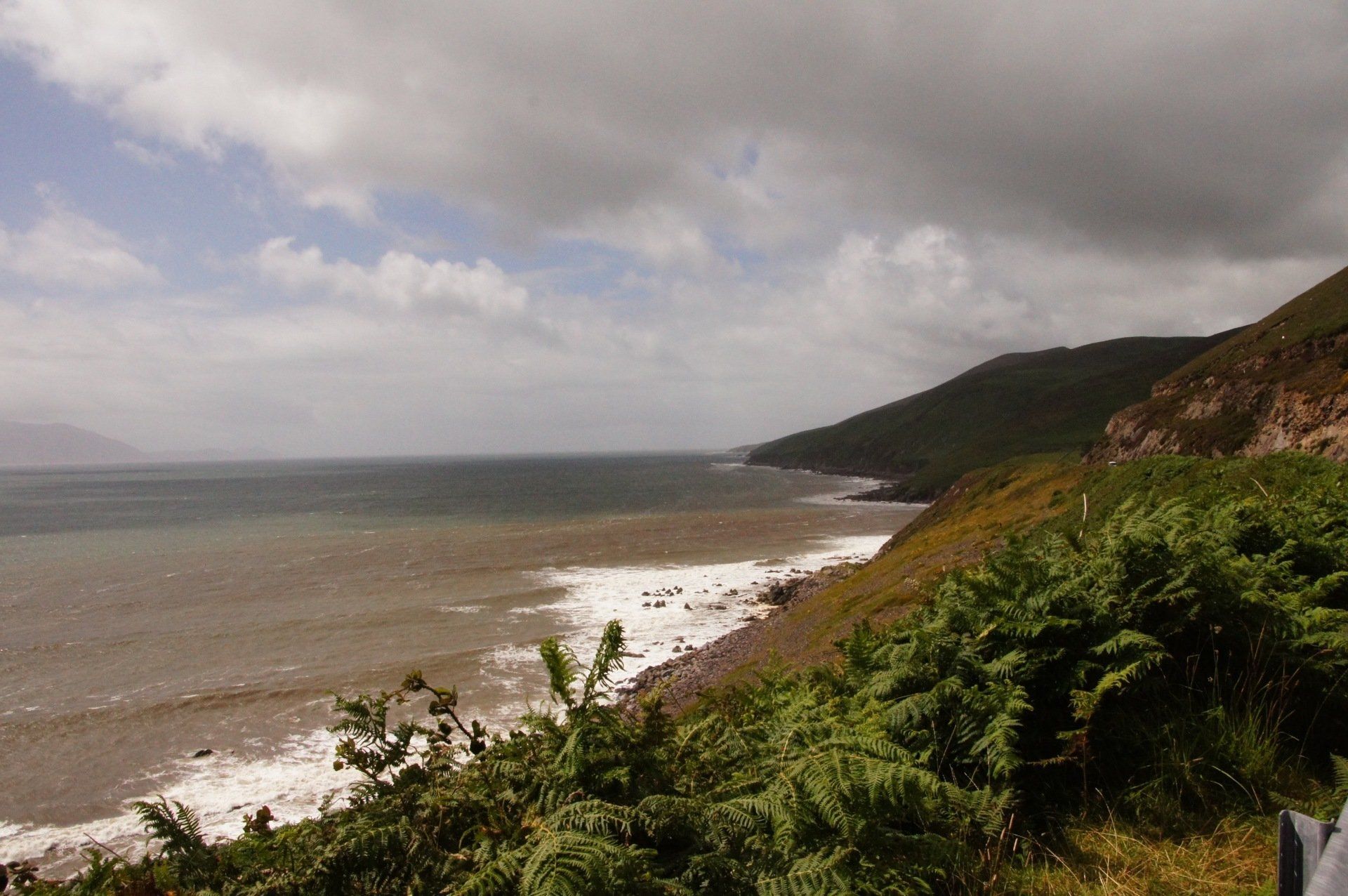 A view of the ocean from a cliff on a cloudy day