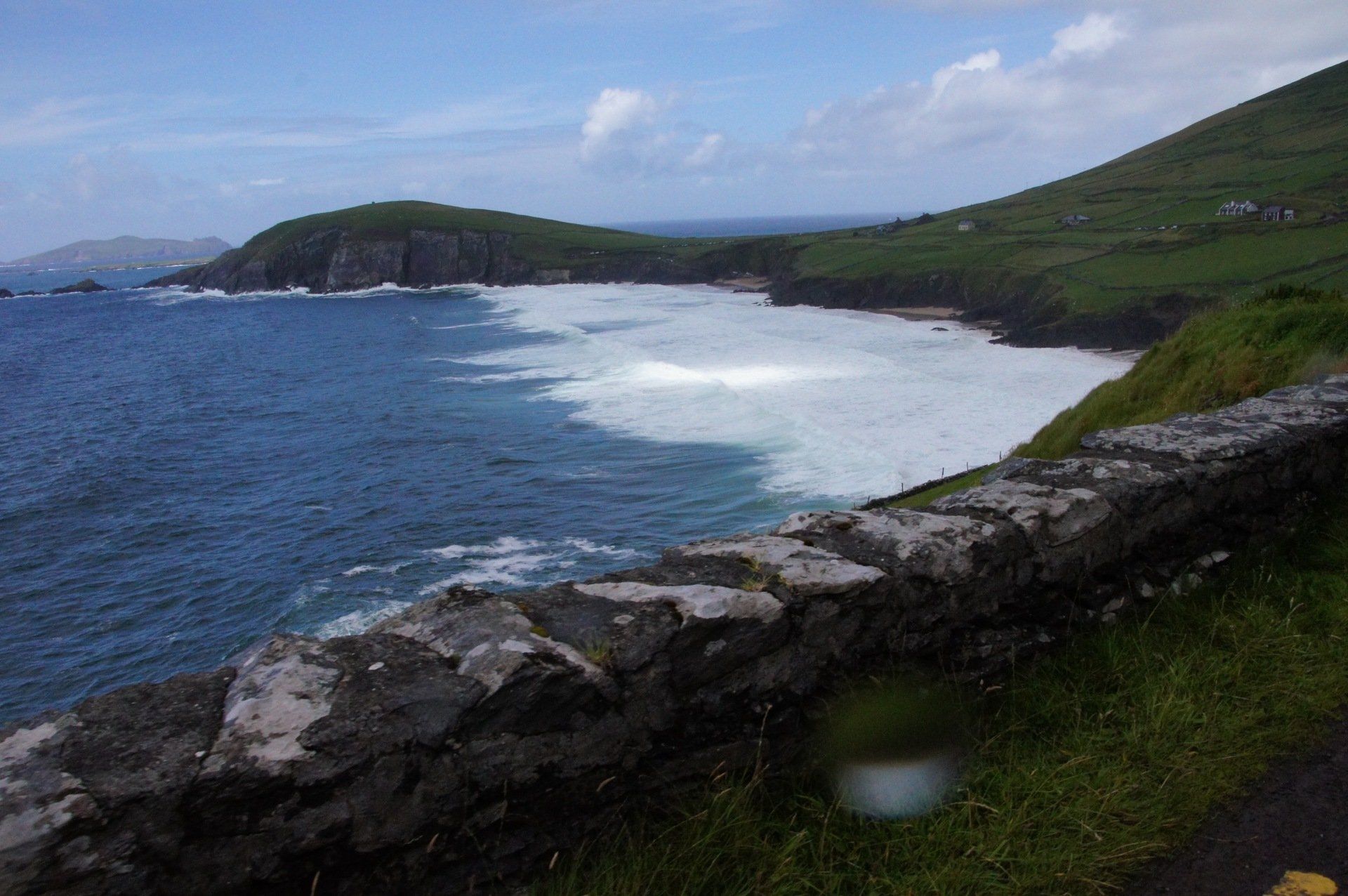 A cliff overlooking the ocean with waves crashing on the shore
