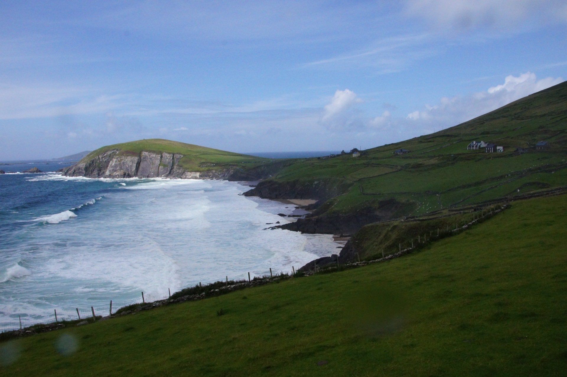A cliff overlooking the ocean with waves crashing on the shore.