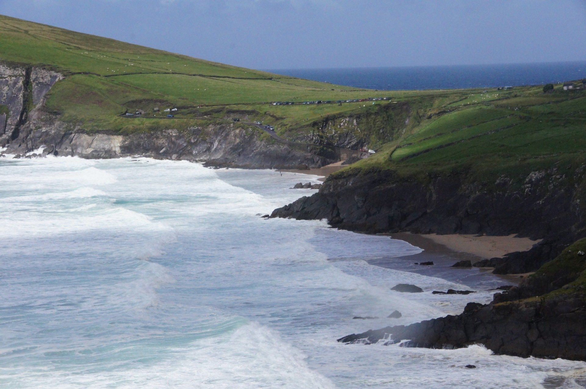 A cliff overlooking the ocean with waves crashing on the shore