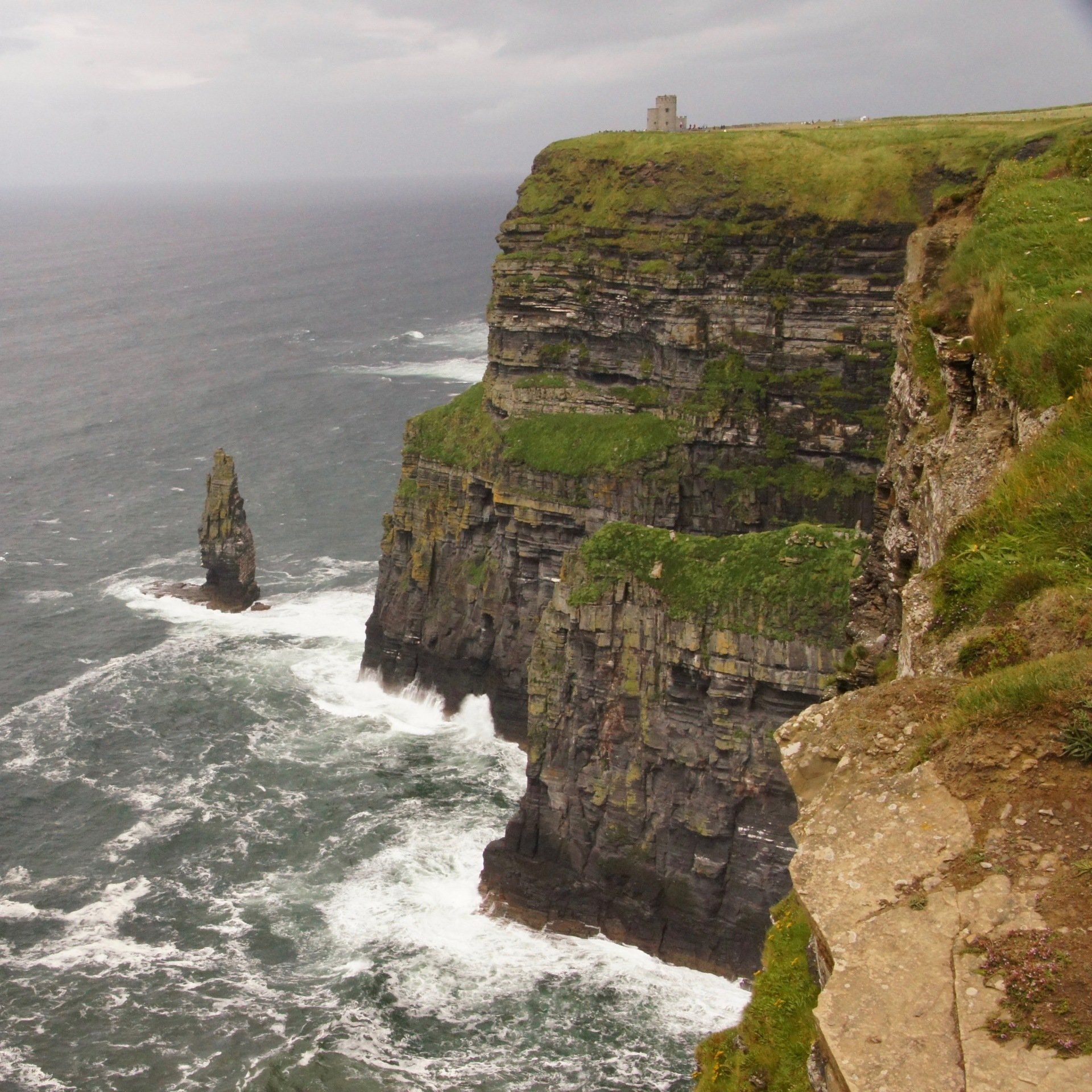 A cliff overlooking the ocean with waves crashing on it