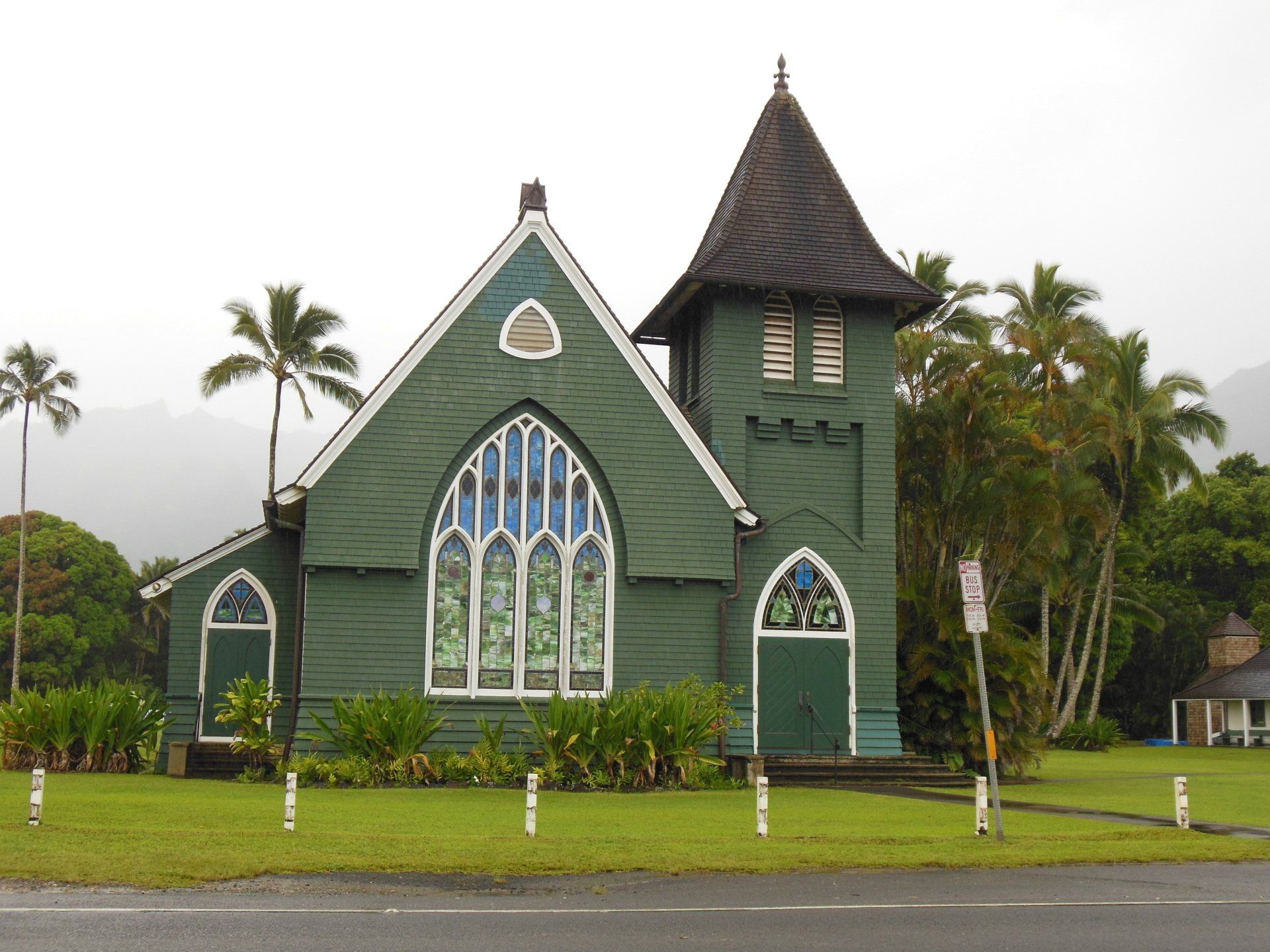 A green church with a tower and stained glass windows