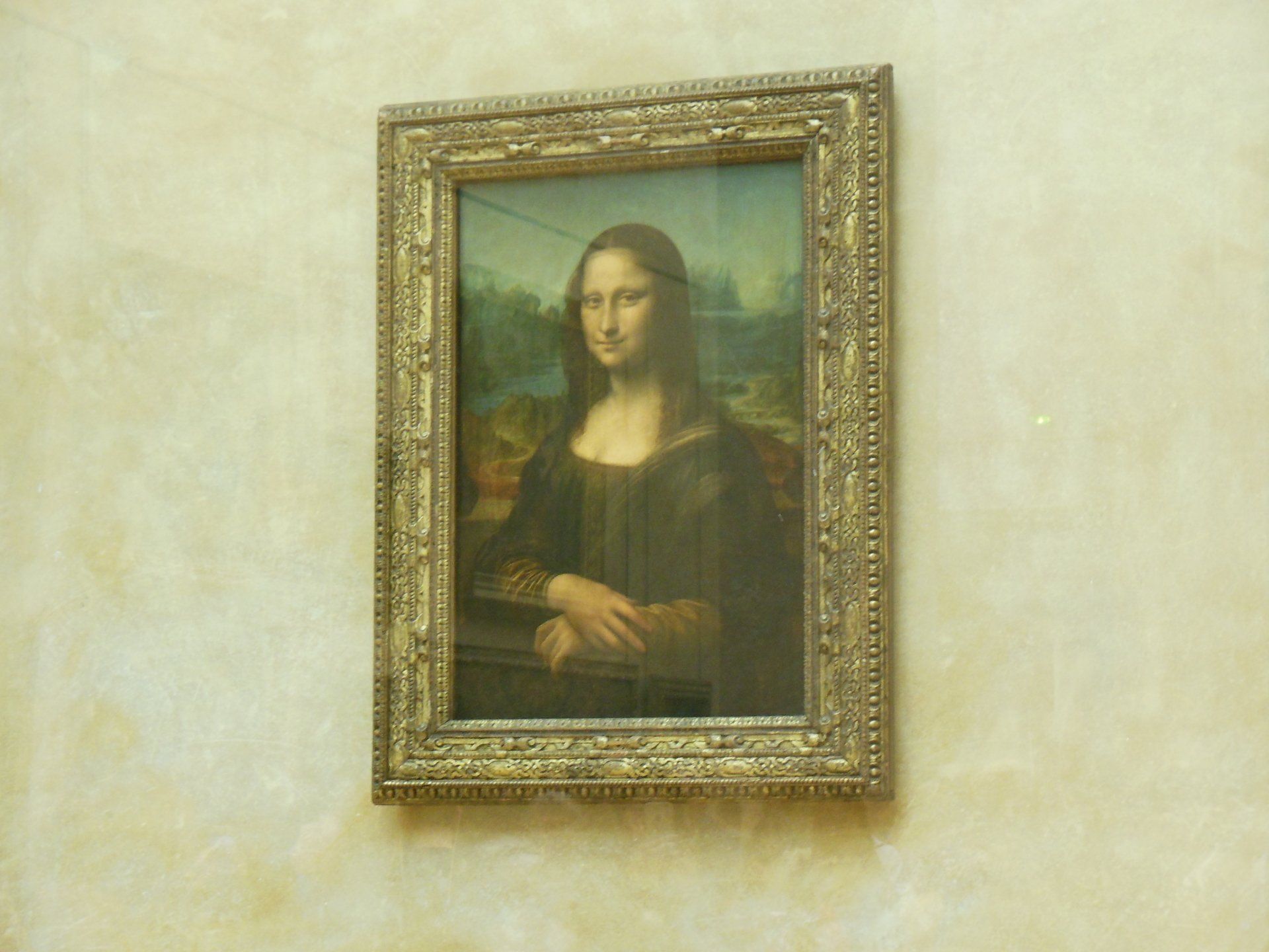 A painting of a woman in a gold frame hangs on a wall