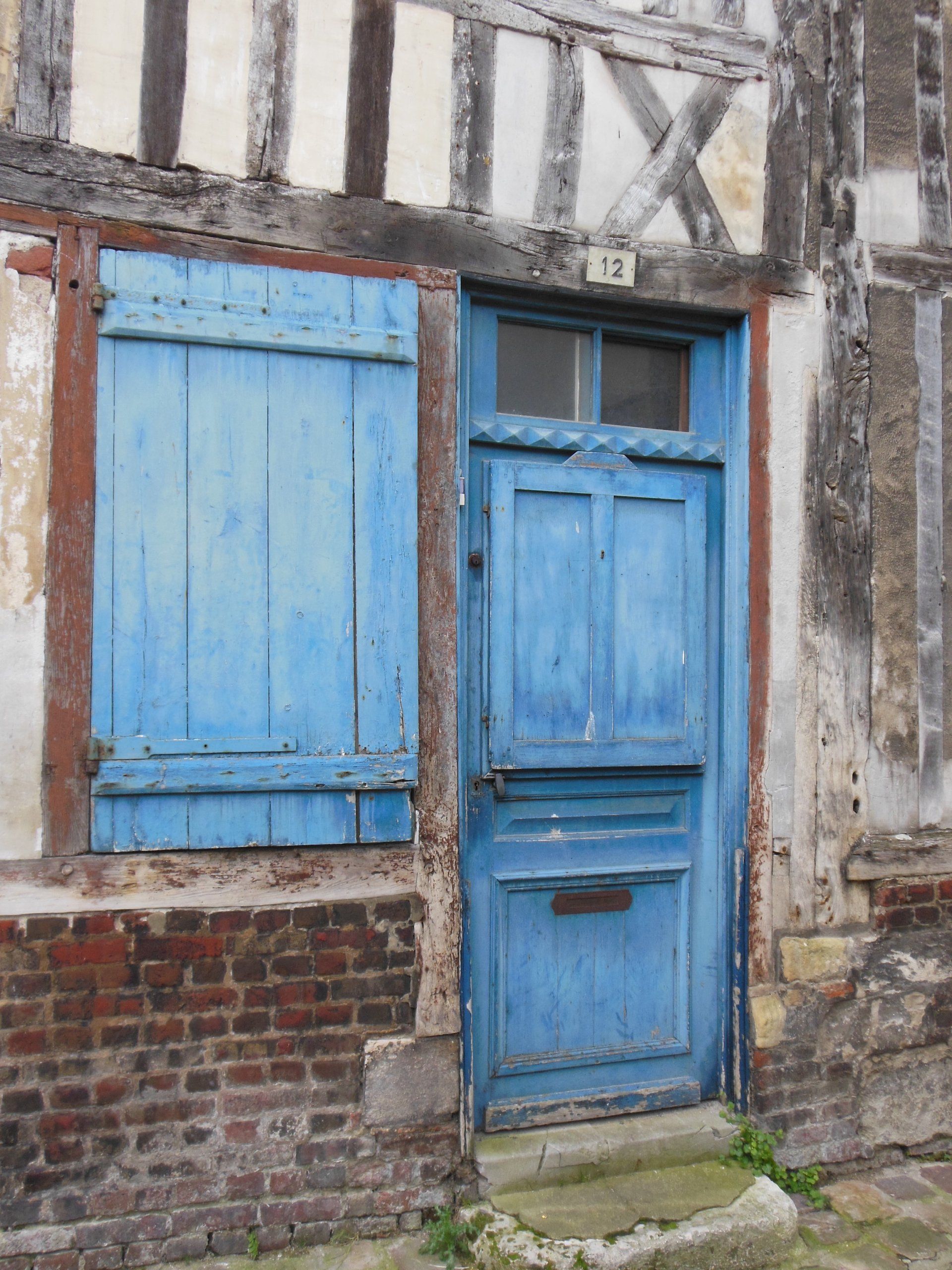 A blue door with blue shutters on a brick building