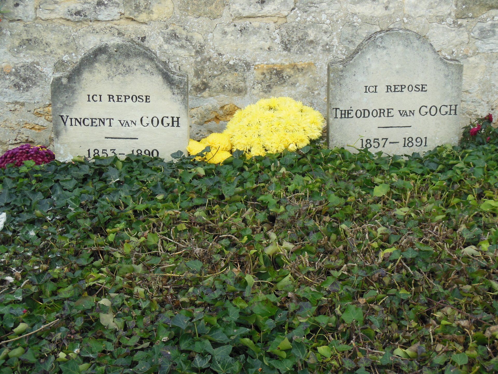 A grave of vincent van gogh is surrounded by ivy and flowers