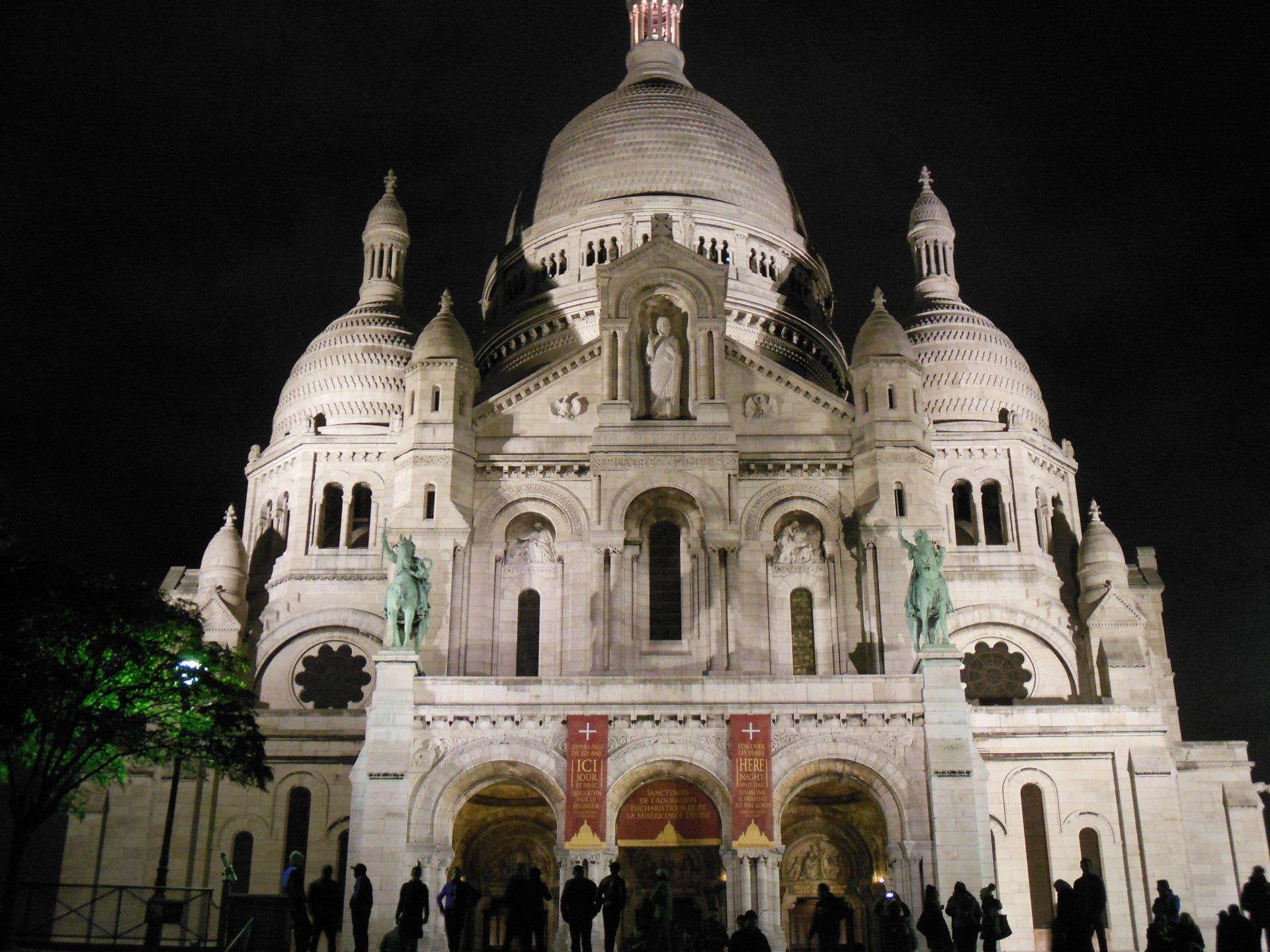 A group of people are standing in front of a large building at night