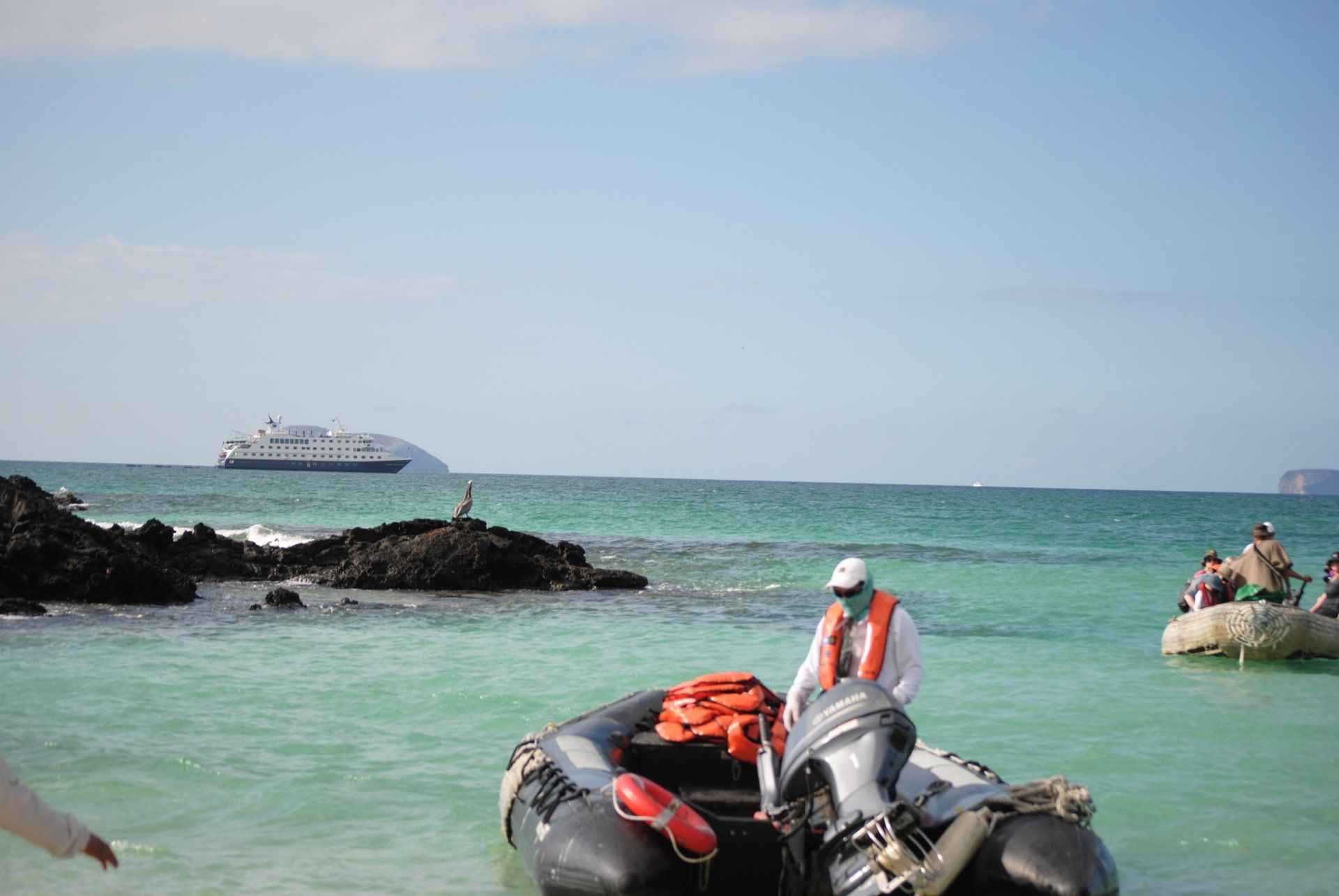 A group of people in boats in the ocean with a cruise ship in the background