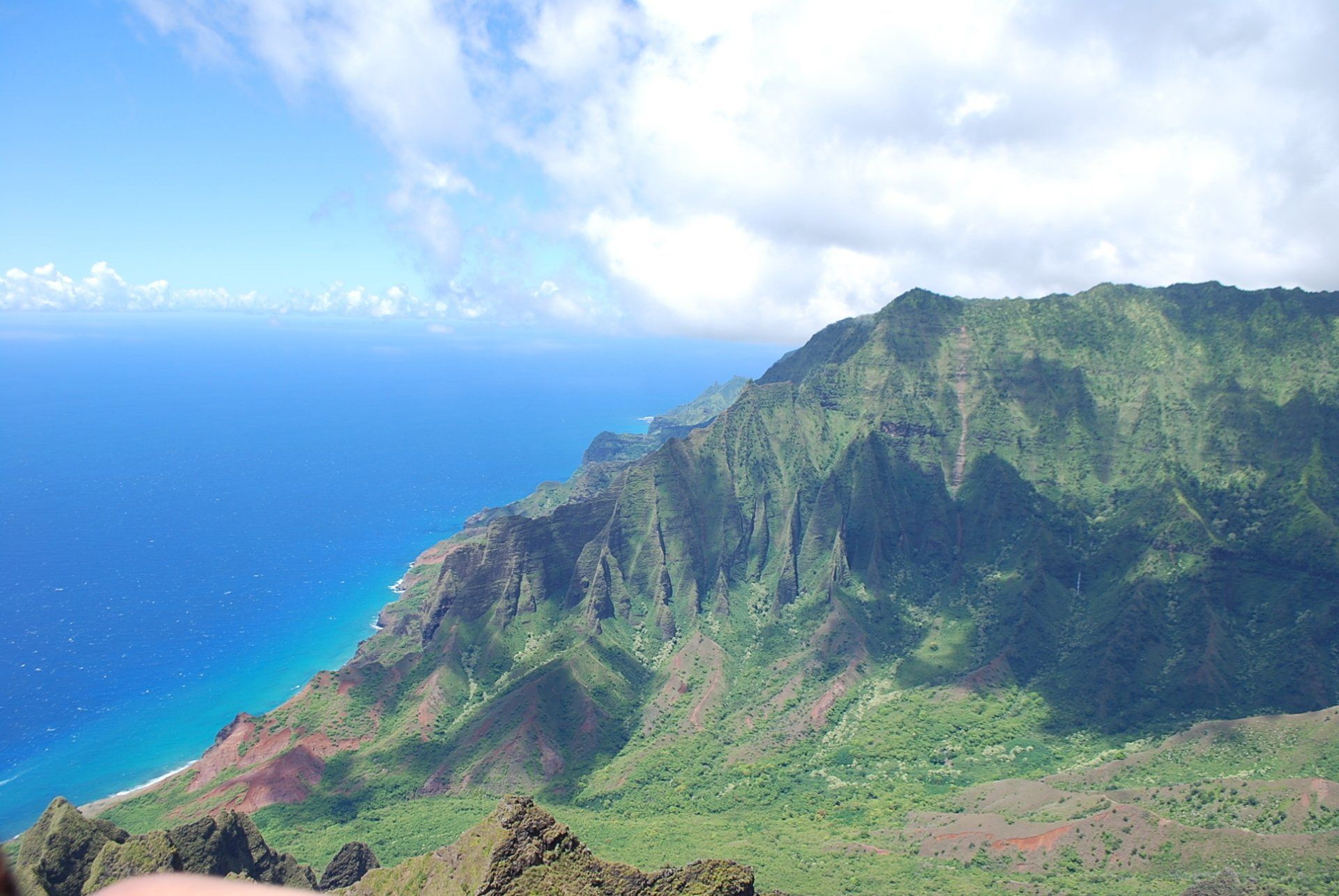A person is pointing at a mountain with the ocean in the background