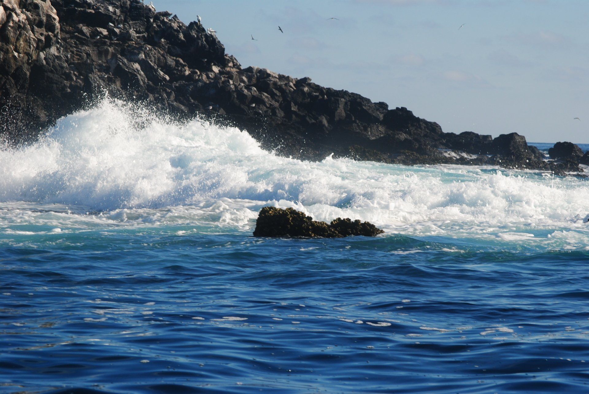 Waves crashing against a rocky shoreline on a sunny day