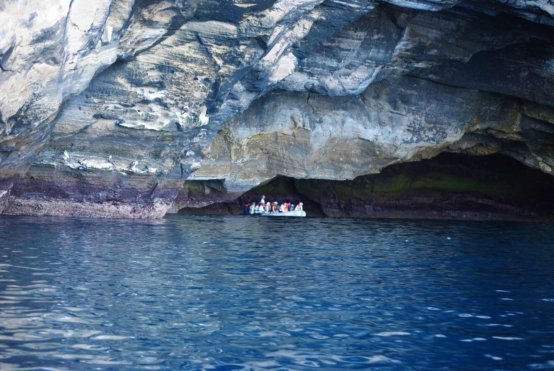 A boat is in a cave in the middle of the ocean.