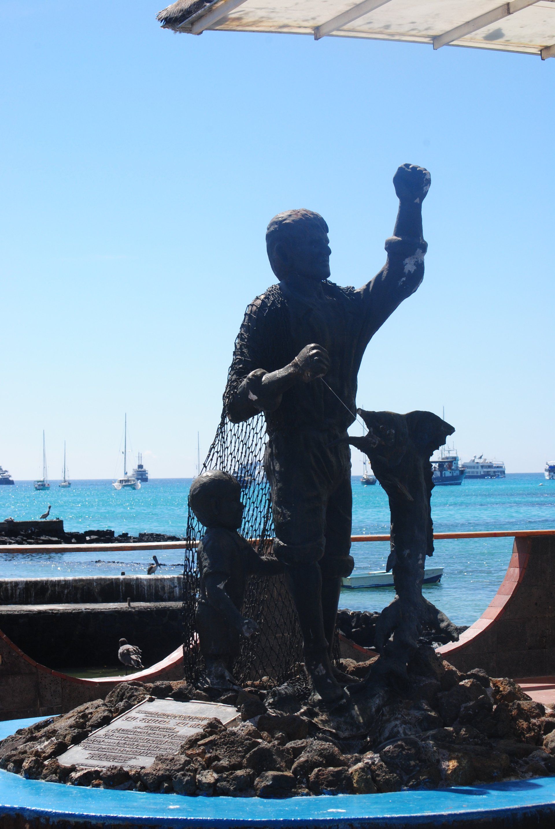 A statue of a man holding a fishing net in front of the ocean