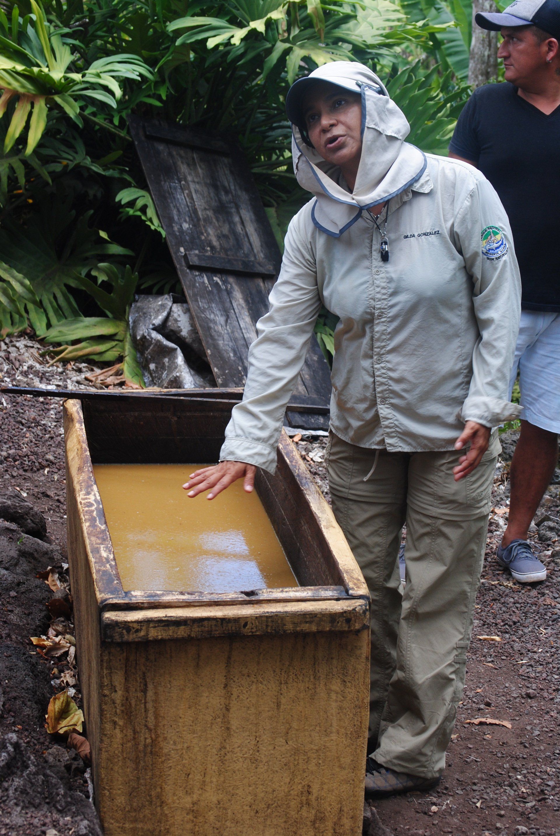 A woman is standing next to a wooden box filled with water.