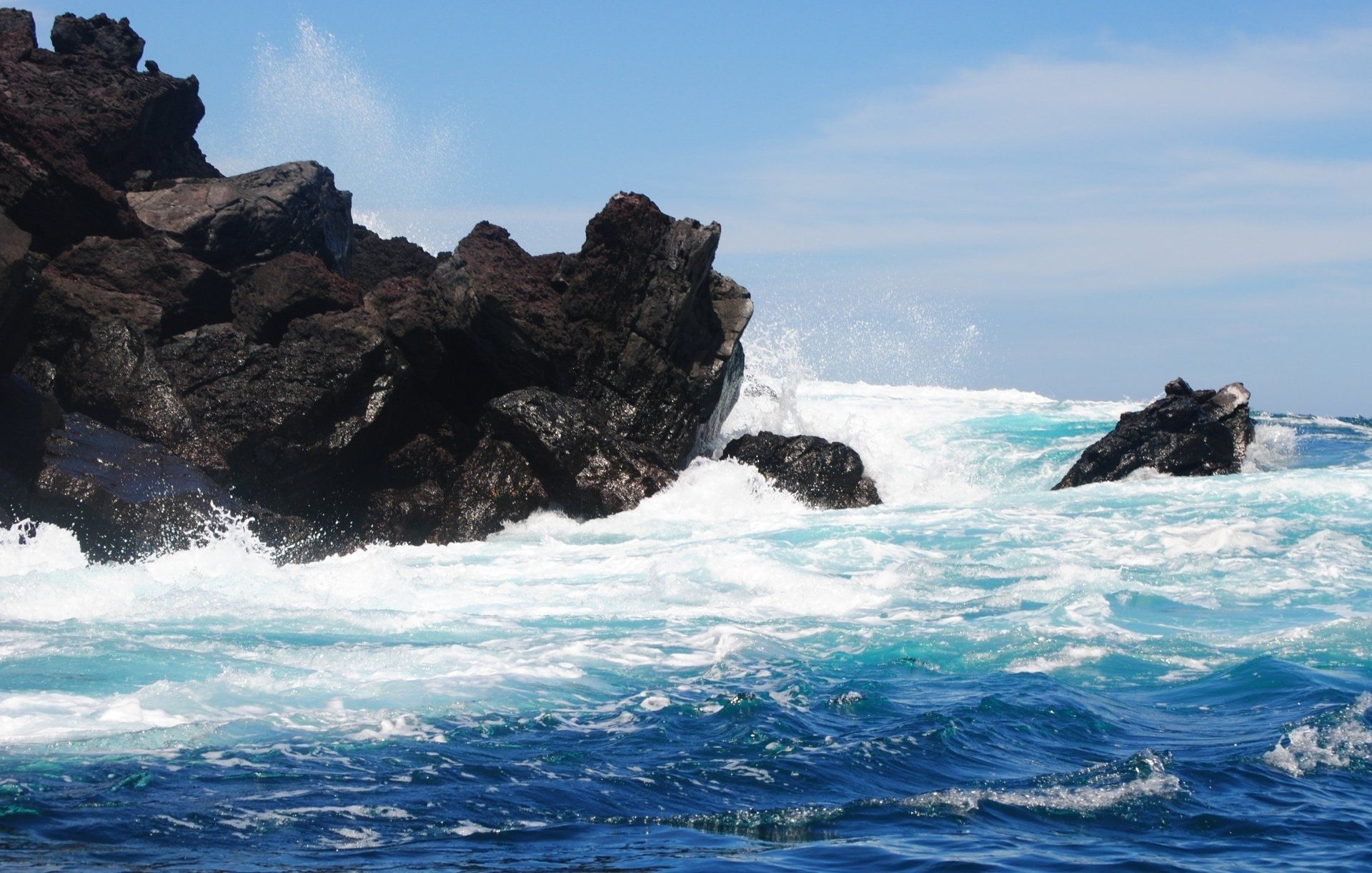 Waves crashing against a rocky shoreline on a sunny day