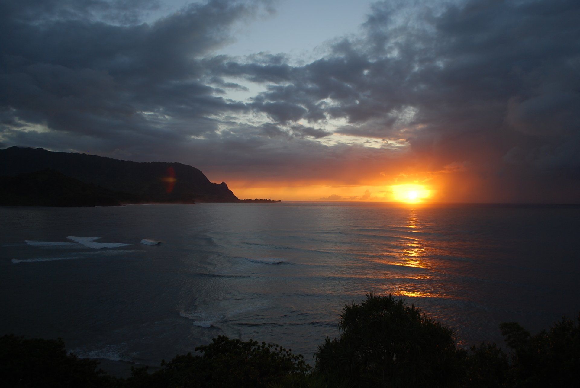 A sunset over a body of water with a mountain in the background
