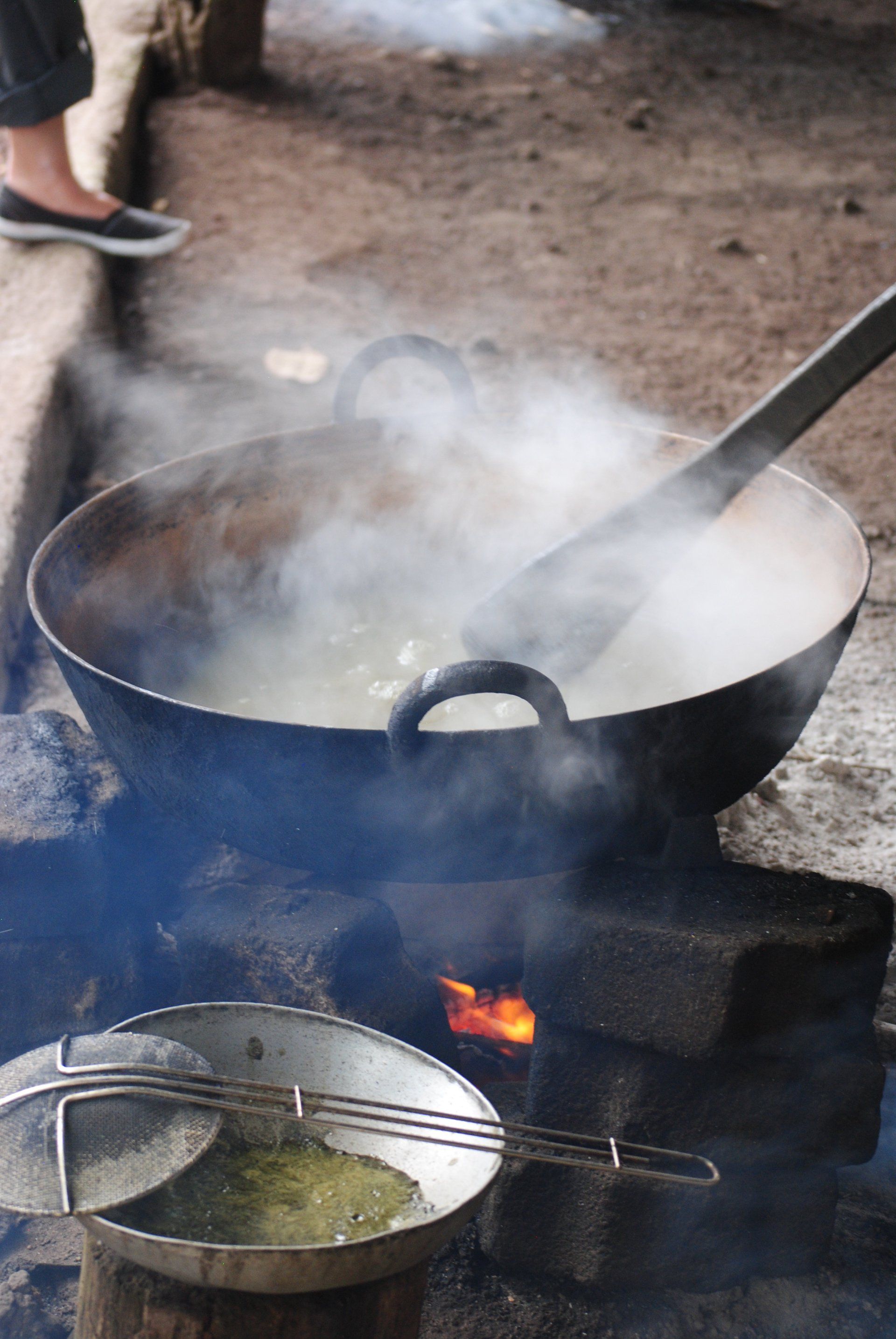 A person is cooking food in a pot over a fire.