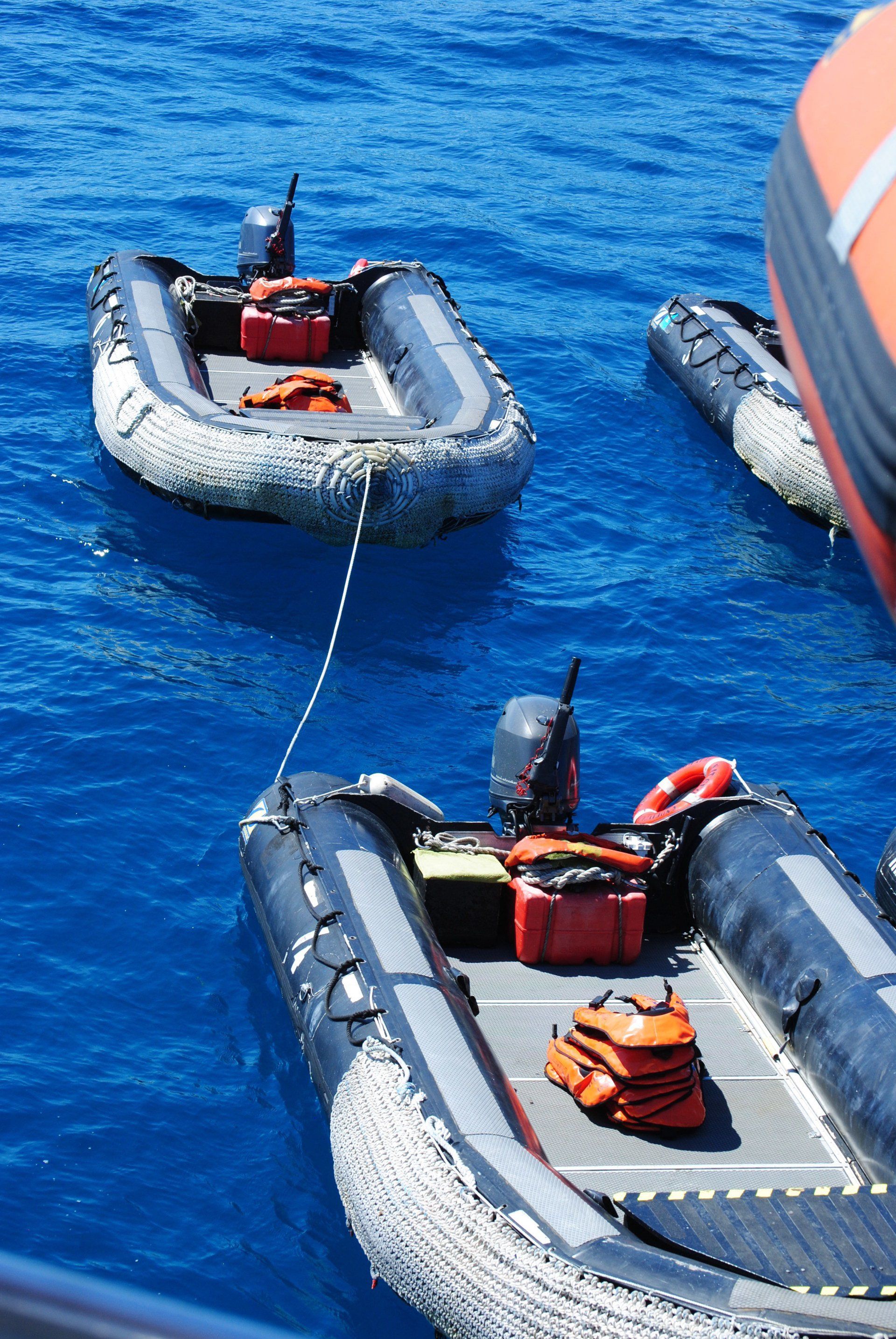 Three inflatable boats are tied to a boat in the ocean