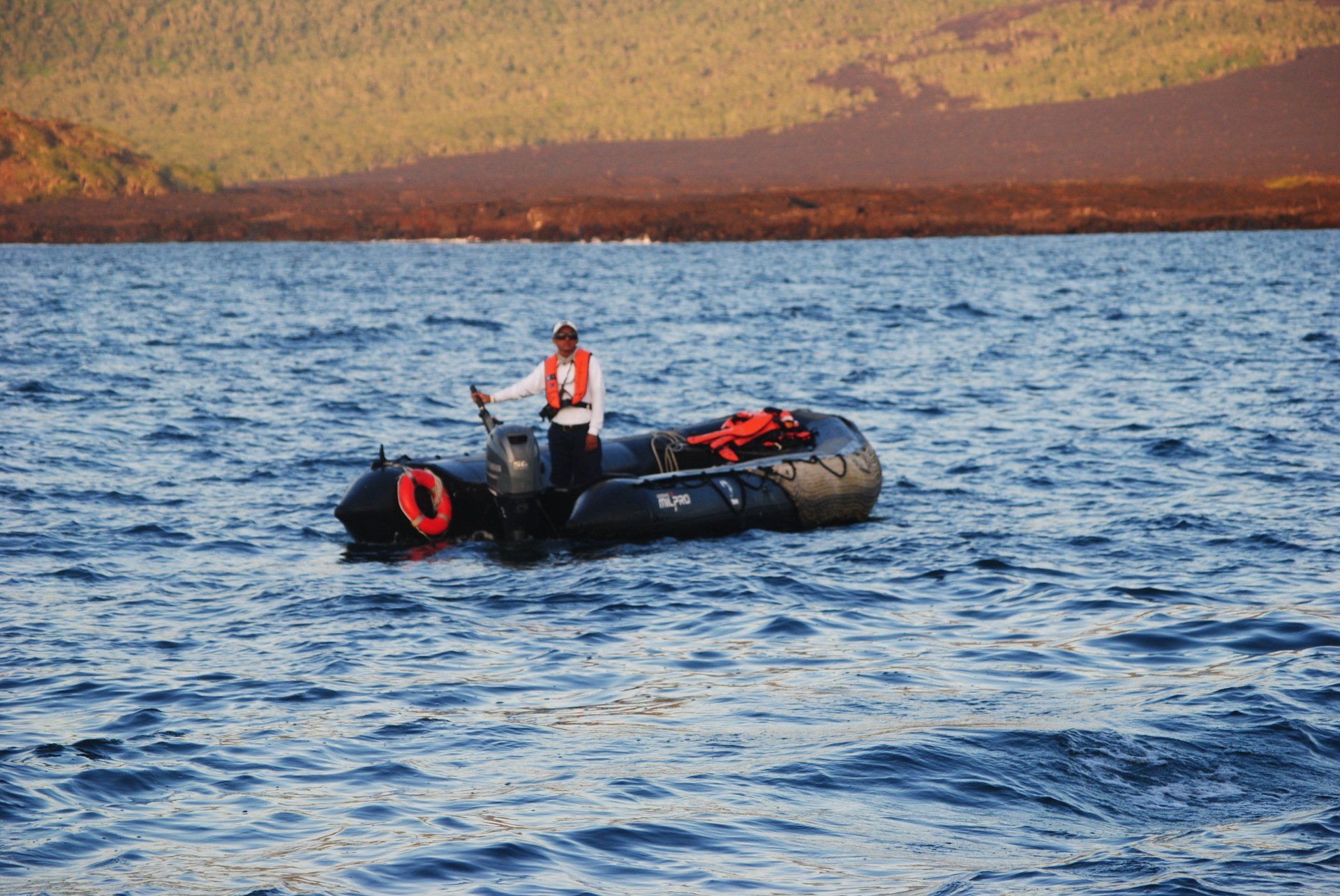 A man in a life vest is in a small boat in the water.