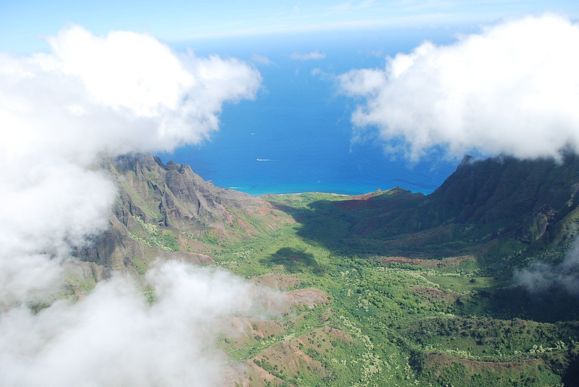An aerial view of a valley with mountains and clouds