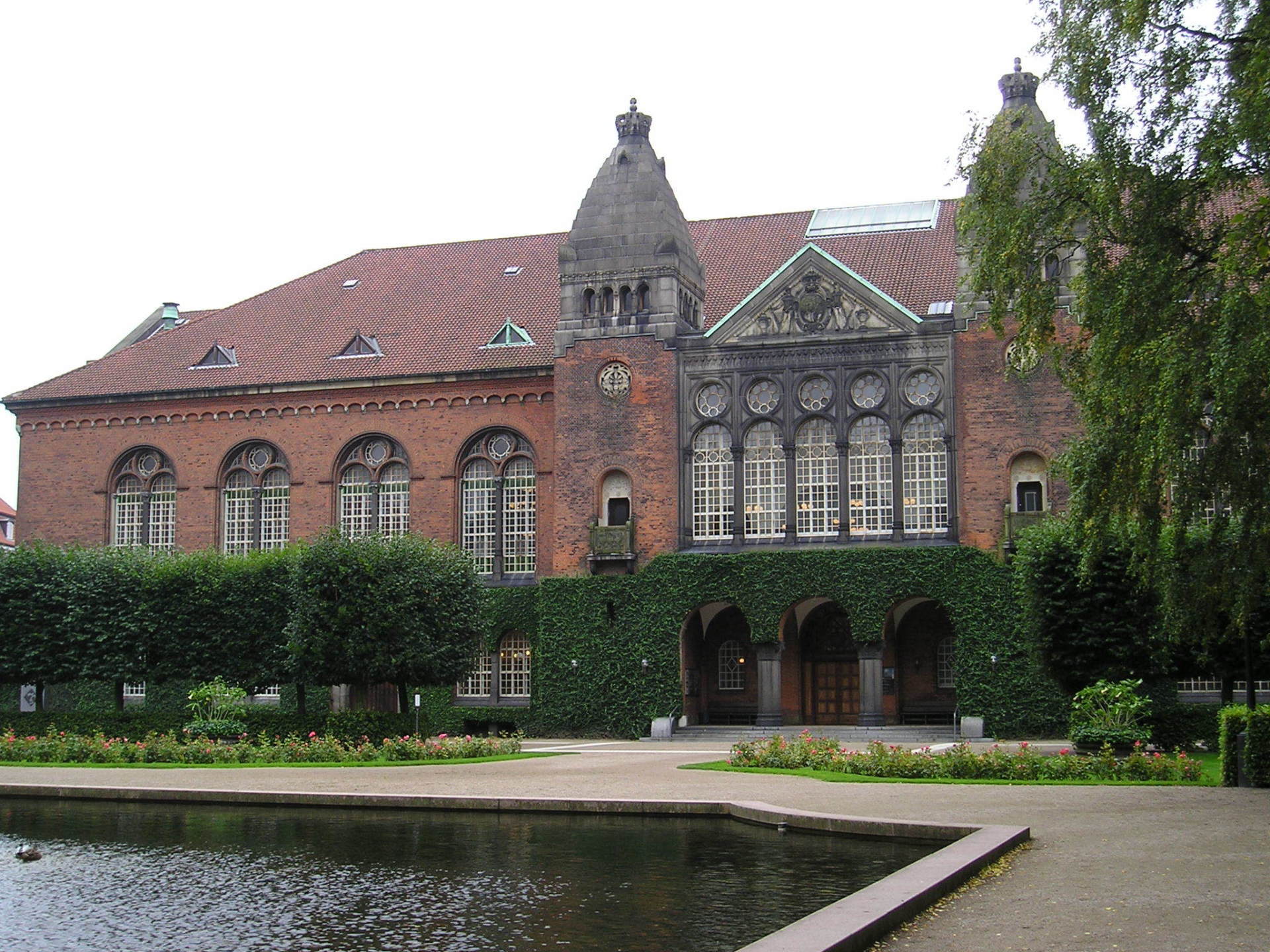A large brick building with a pond in front of it