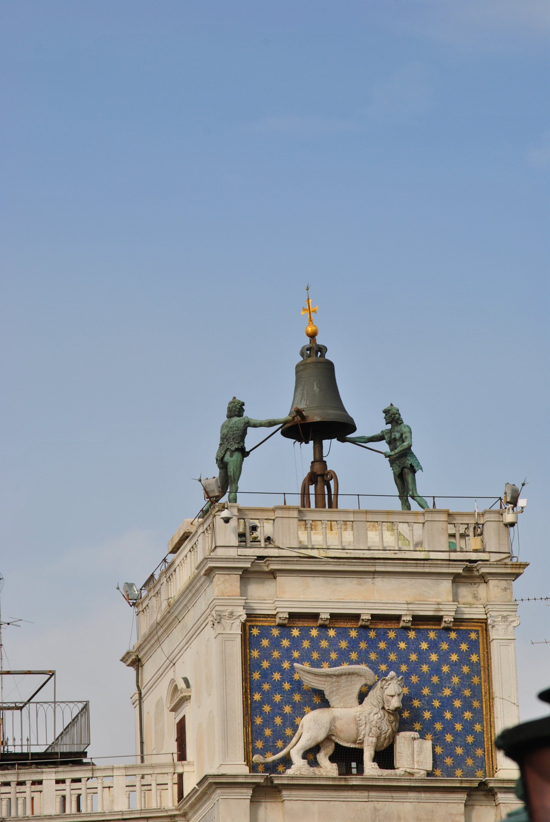 A statue of a lion holding a bell on top of a building