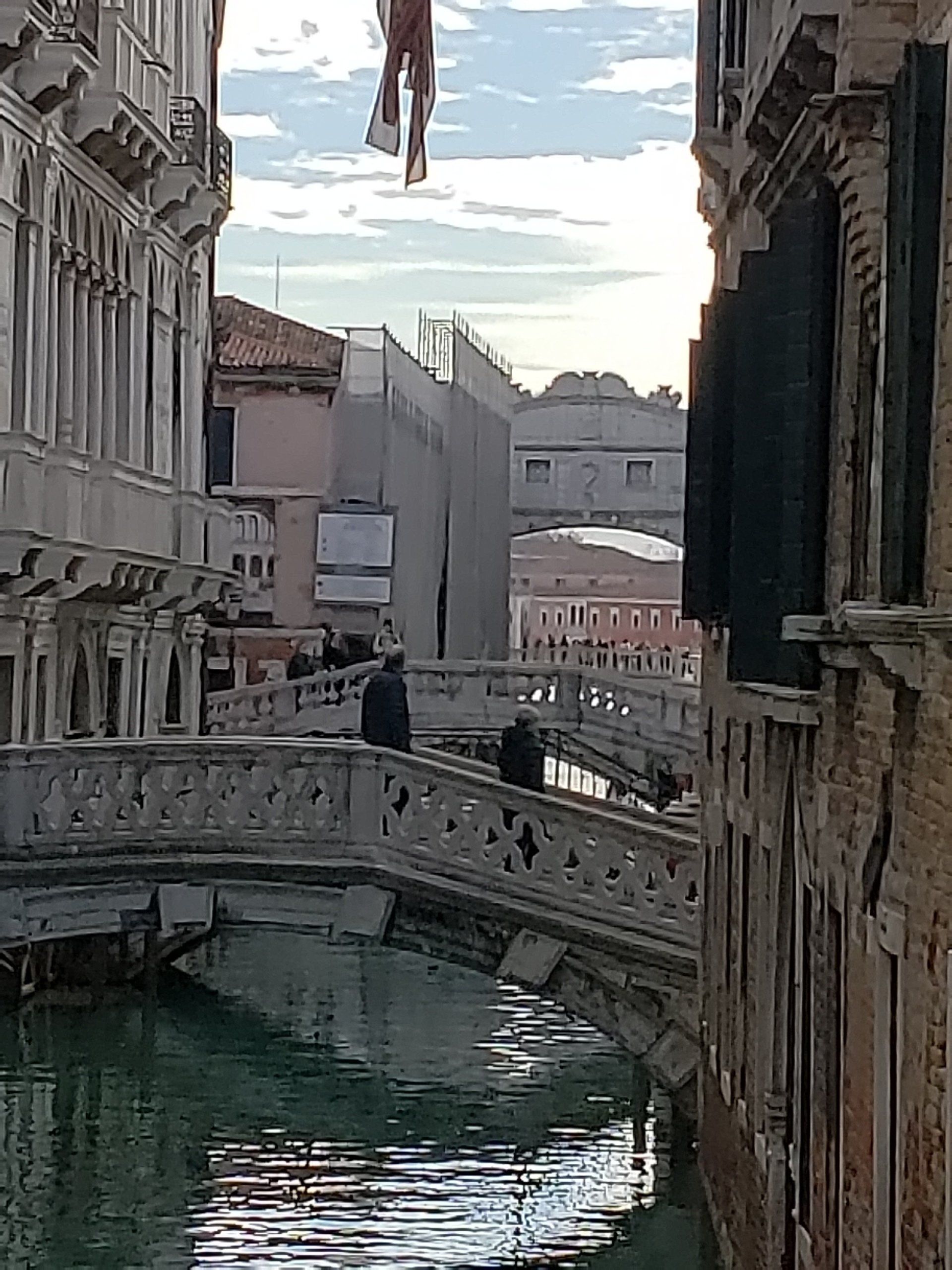 A bridge over a river between two buildings in a city.